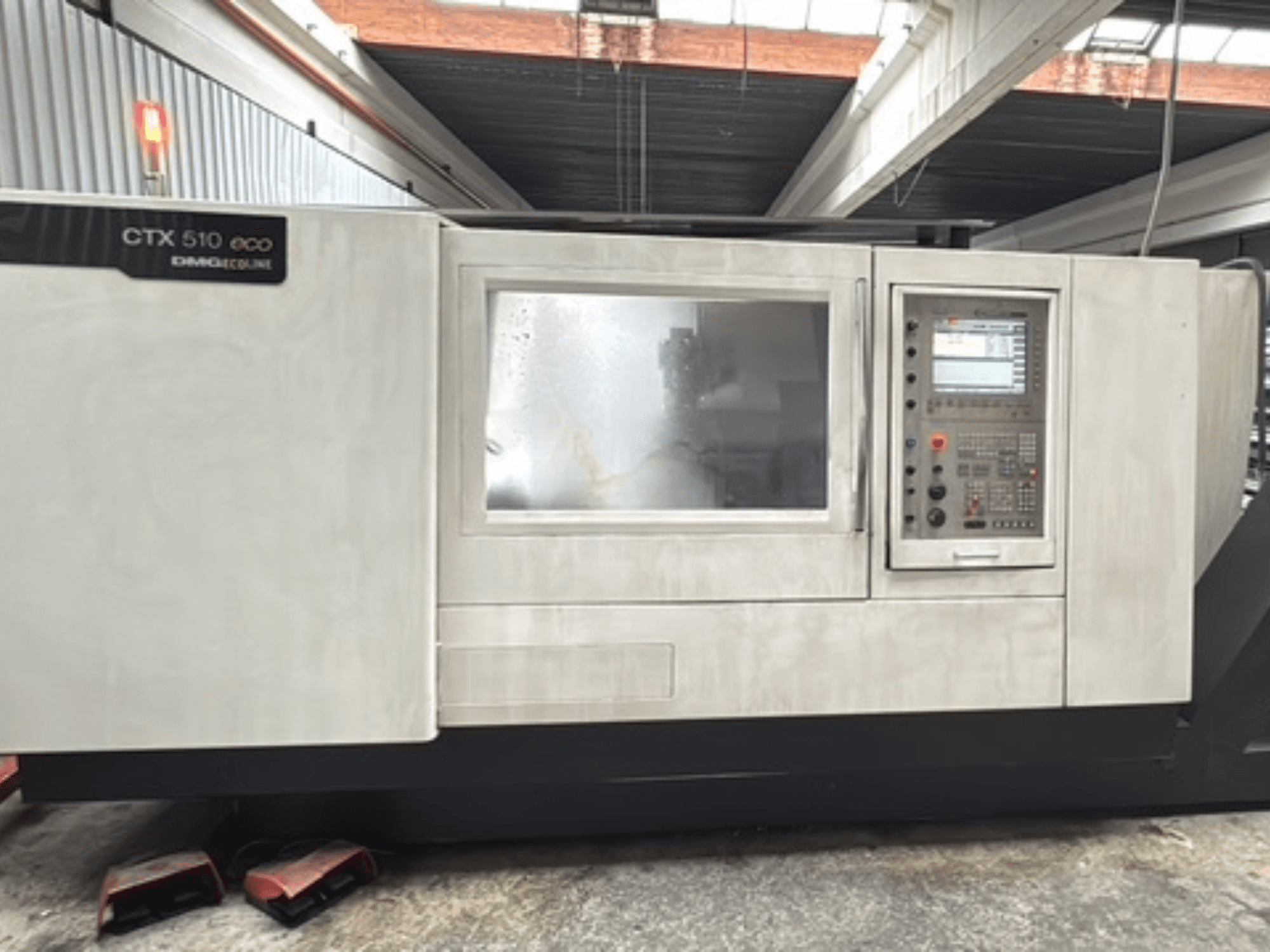 Горизонтальний токарний верстат DMG CTX 510 ecoline, вид спереду, на якому видно панель управління та вікно на корпусі верстата.