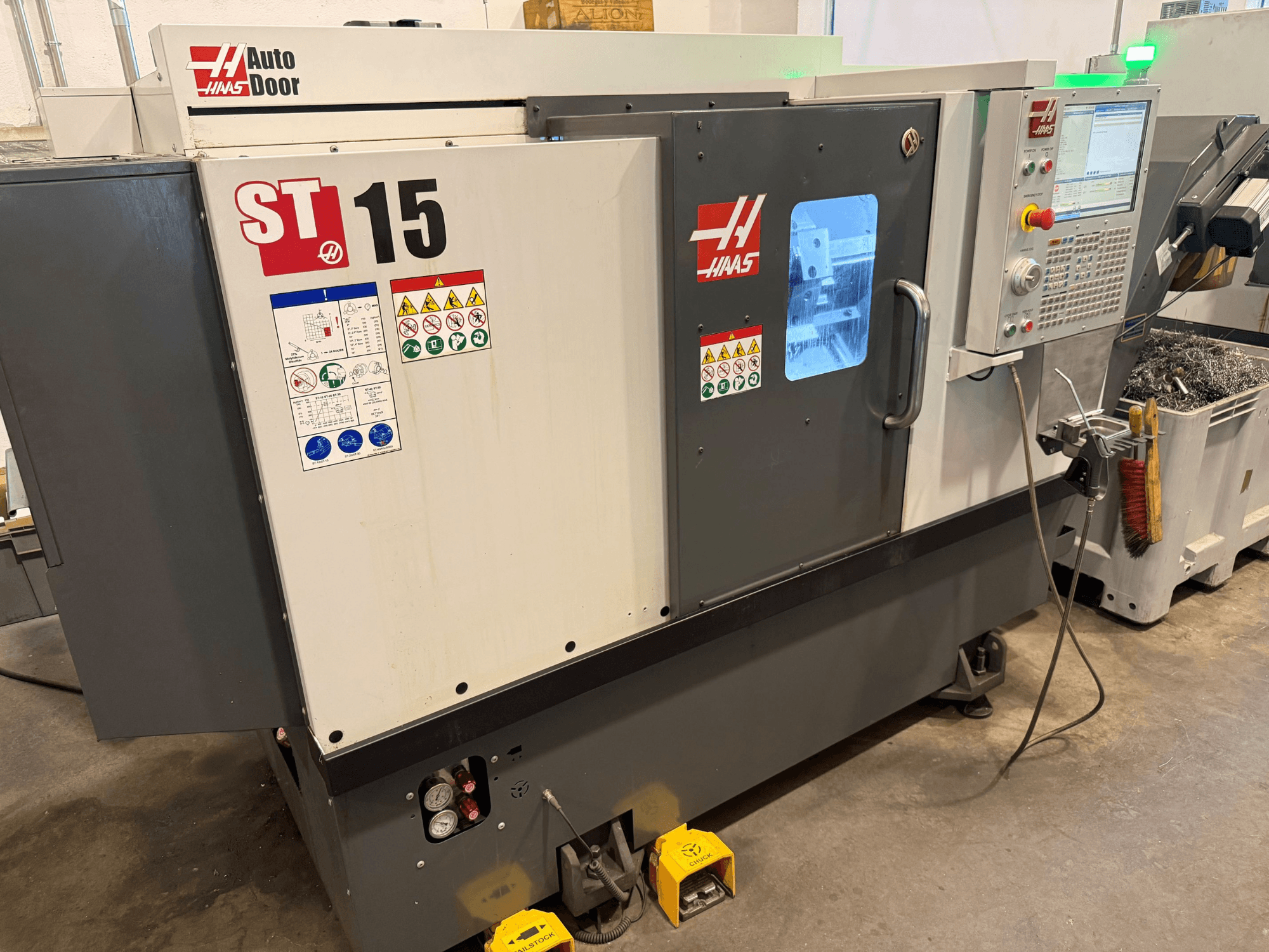 Горизонтальний токарний верстат HAAS ST 15, вид спереду, на якому видно панель управління, автоматичні дверцята та технічні індикатори.