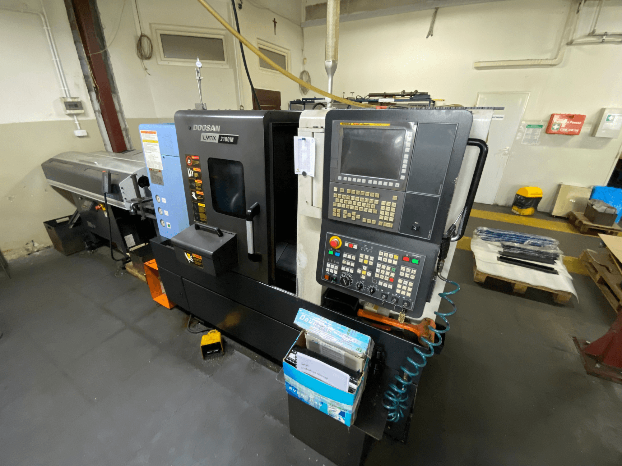 Горизонтальний токарний верстат DOOSAN LYNX 2100MA у боковому ракурсі: на фото зображено панель управління, інструменти та робочу зону.