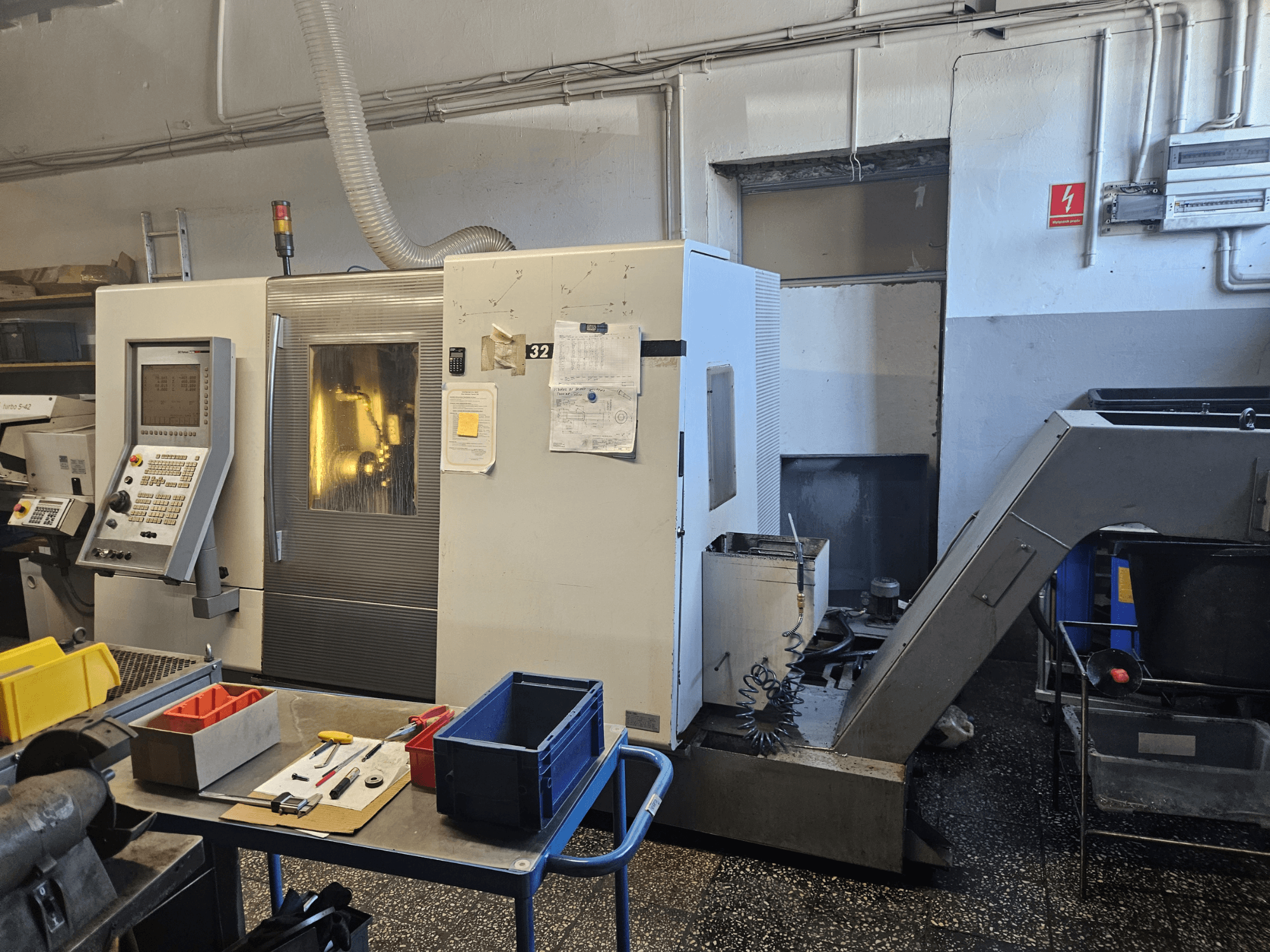 Багатошпиндельний лінійний токарний верстат DMG GILDEMEISTER Sprint 32, вид спереду в майстерні, з панеллю керування та інструментами.