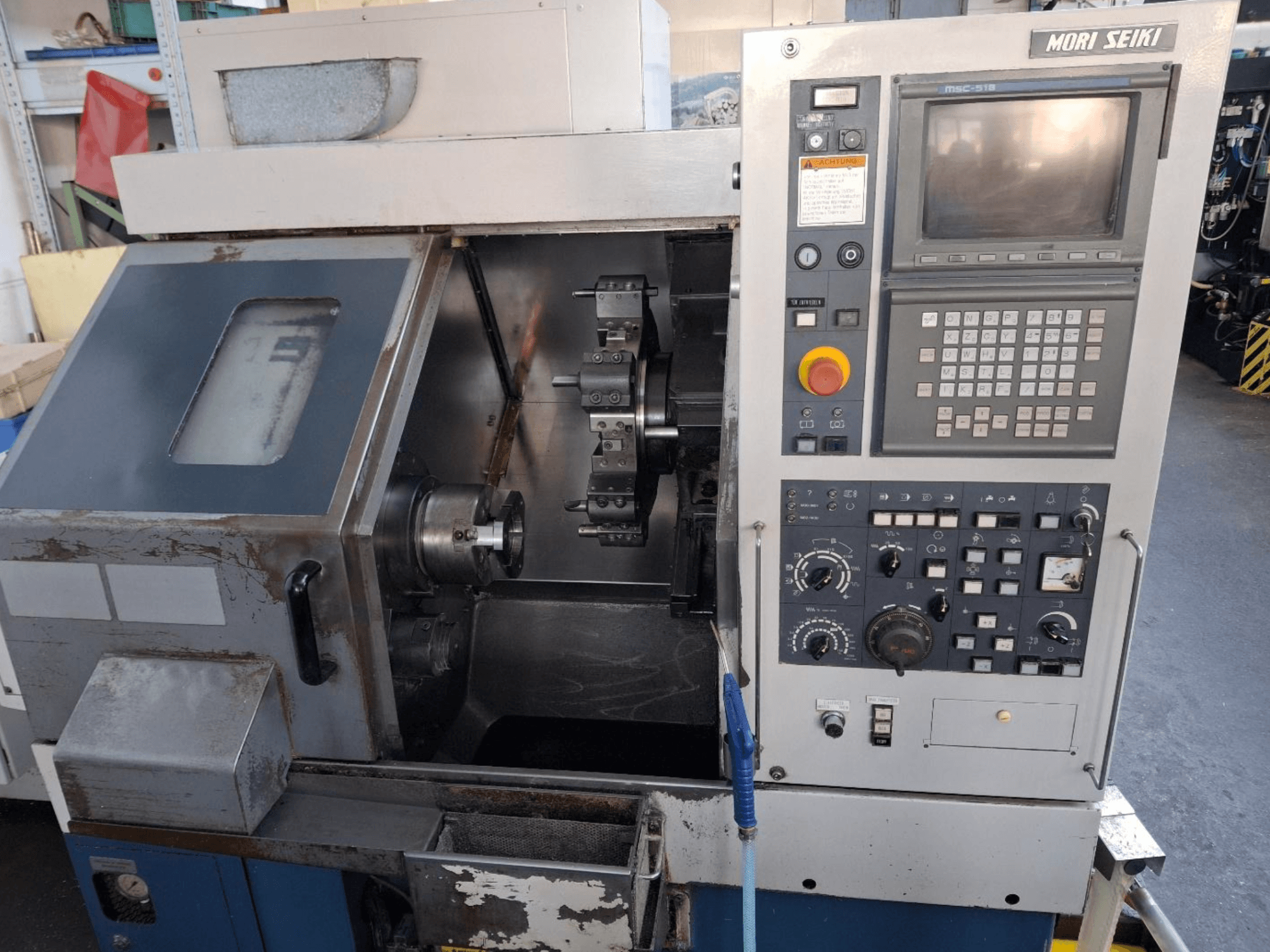 Горизонтальний токарний верстат MORI SEIKI CL 15, вид спереду з панеллю керування та зоною обробки.