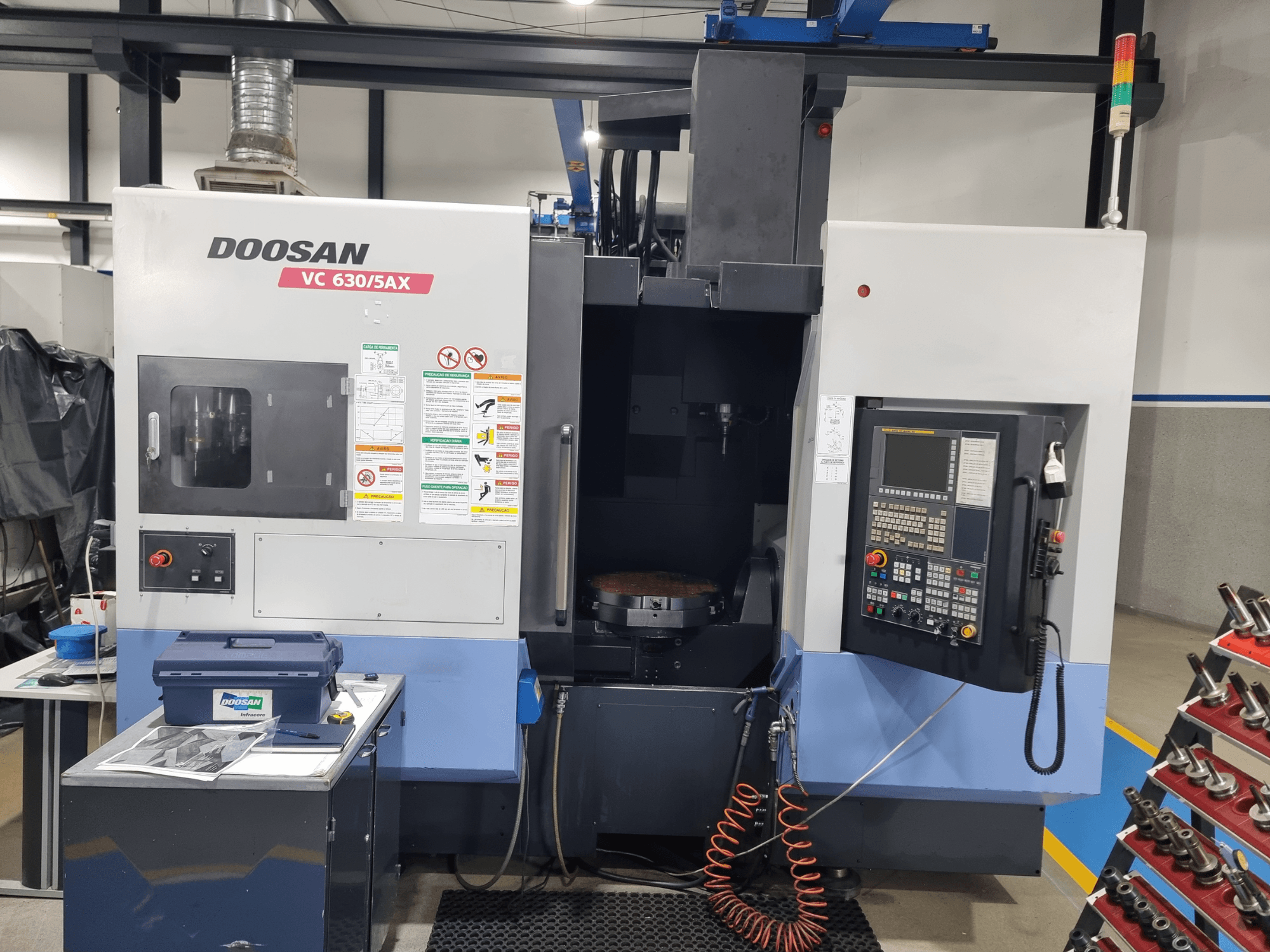Універсальний обробний центр DOOSAN VC 630/5AX, вид спереду, на якому видно панель управління, зону різання та засоби безпеки.