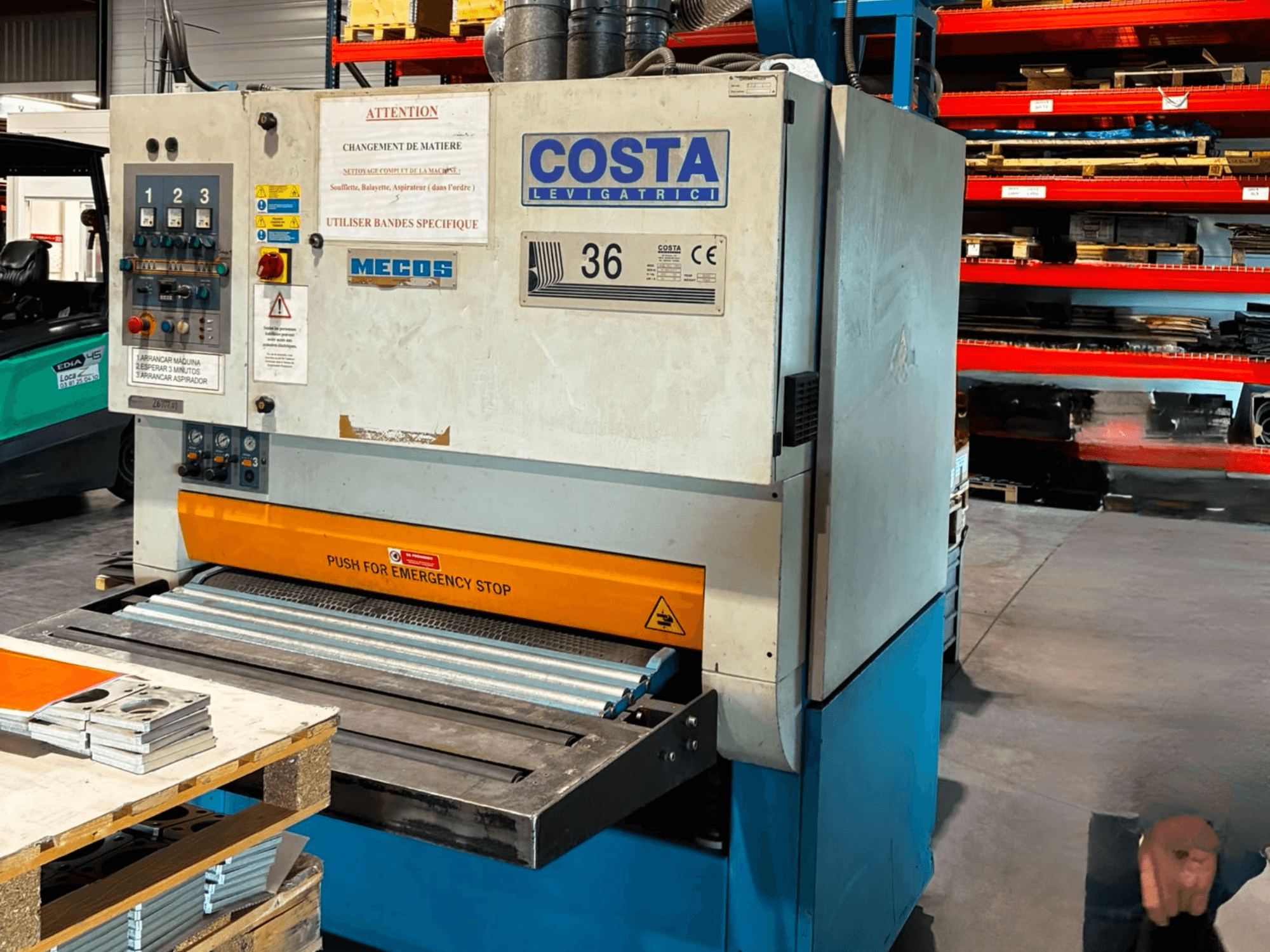 Машина для зняття задирок Costa M36 CCS 1150 у боковому ракурсі: на фото видно панель керування, кнопку аварійної зупинки та поверхню конвеєра.