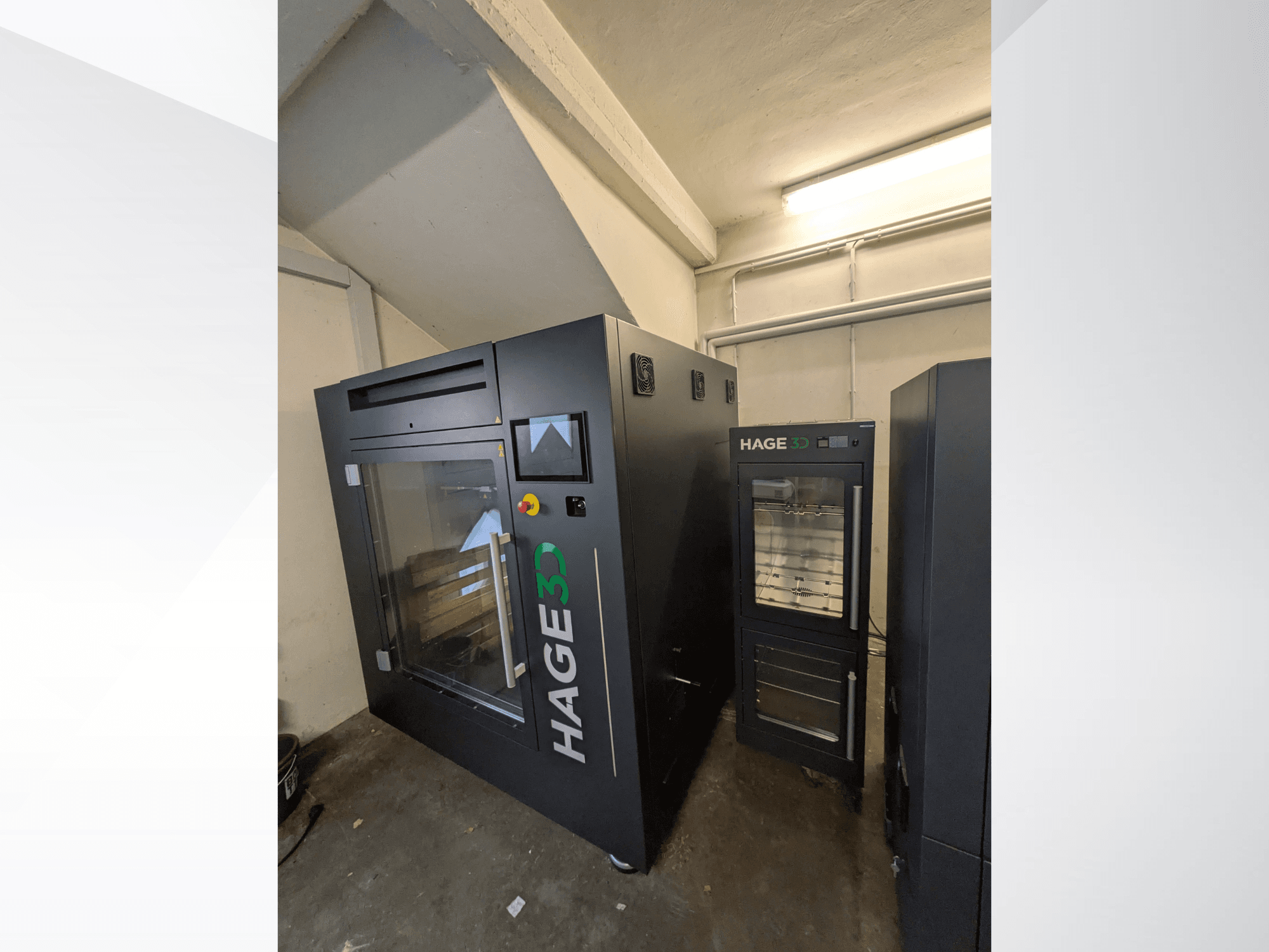 3D-принтер HAGE 3D Precision One для друку з пластику, вид з кута: з прозорими дверцятами та панеллю керування, поруч із ним — місце для зберігання.