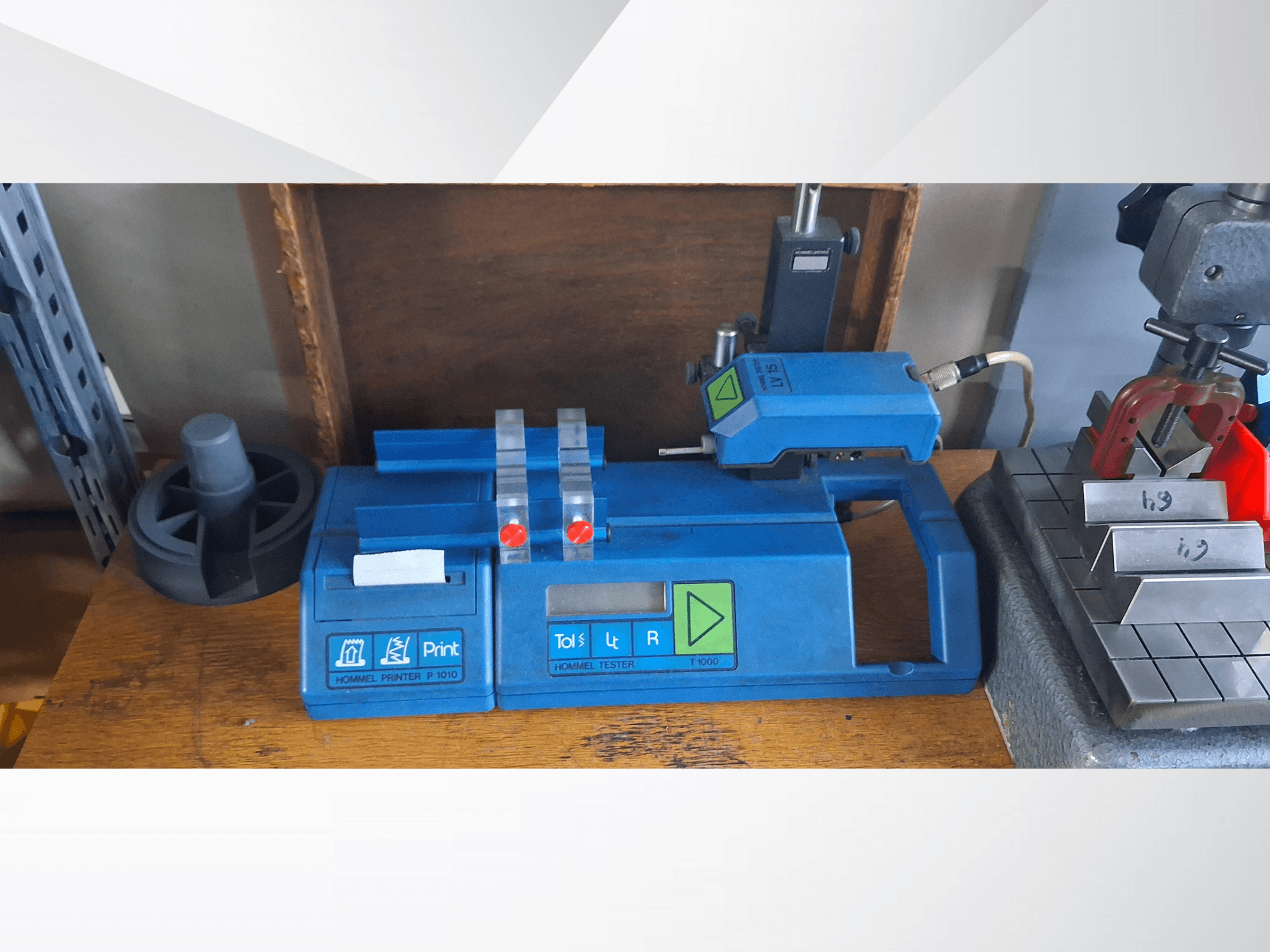 Принтер Hommel P 1010 і тестер T1000 у вигляді збоку, з синім корпусом, кнопками і червоними індикаторами, на робочому столі.