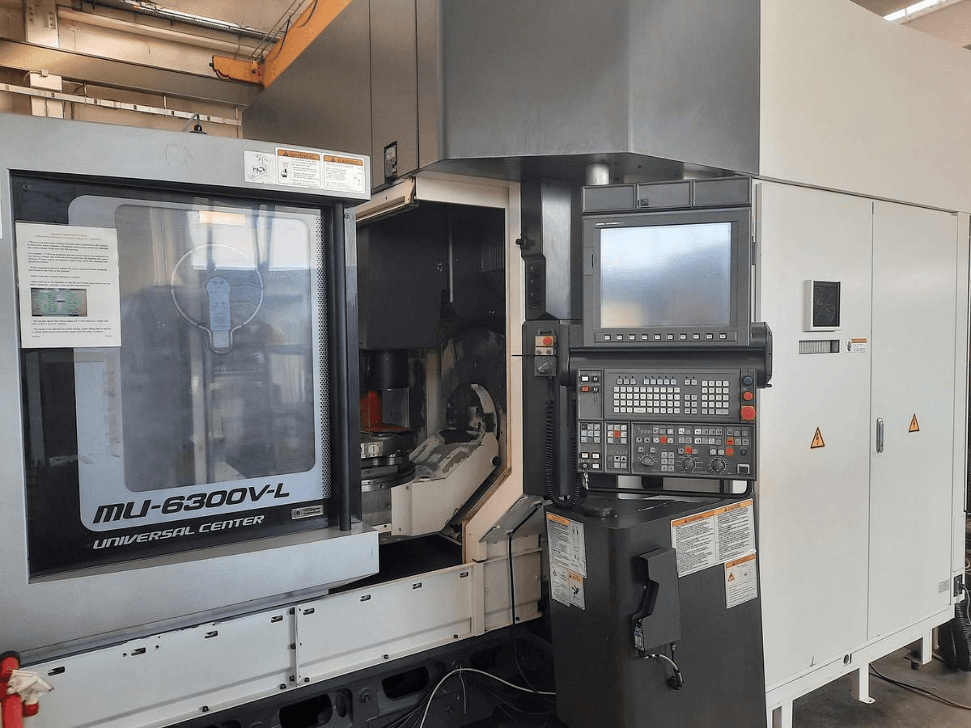 Універсальний центратор MU-6300V-L показаний спереду, з панеллю керування, екраном та інструкцією з експлуатації.