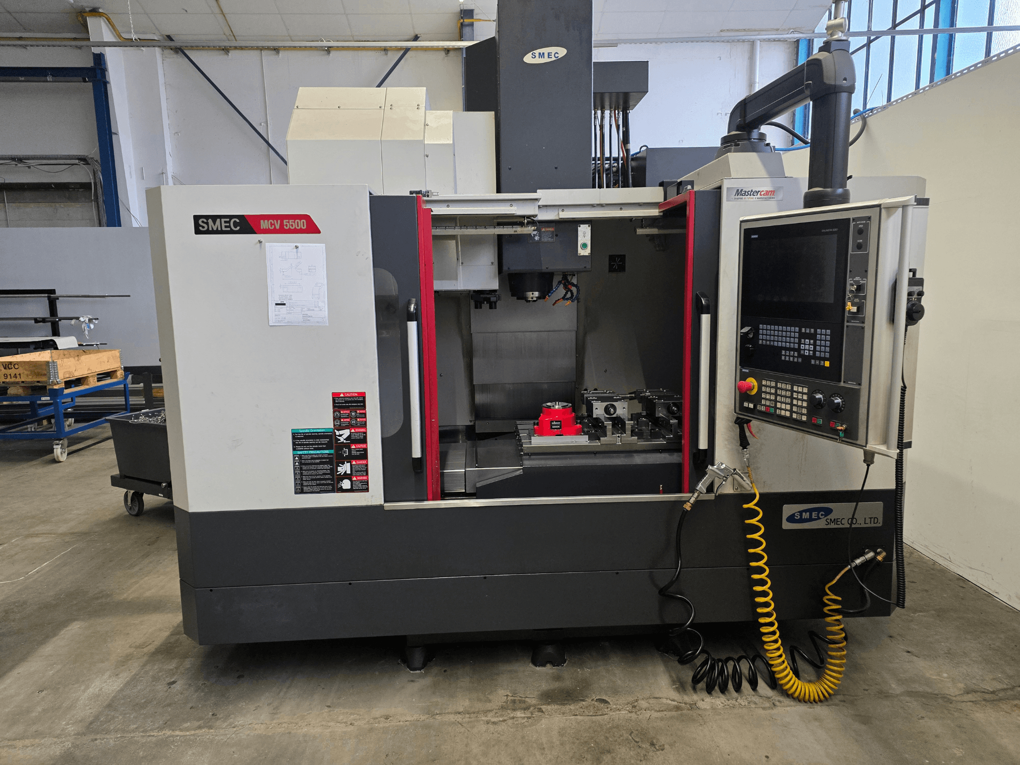 Вертикальний обробний центр SMEC MCV 5500, вид спереду, на якому видно панель керування та внутрішню частину верстата з інструментами.