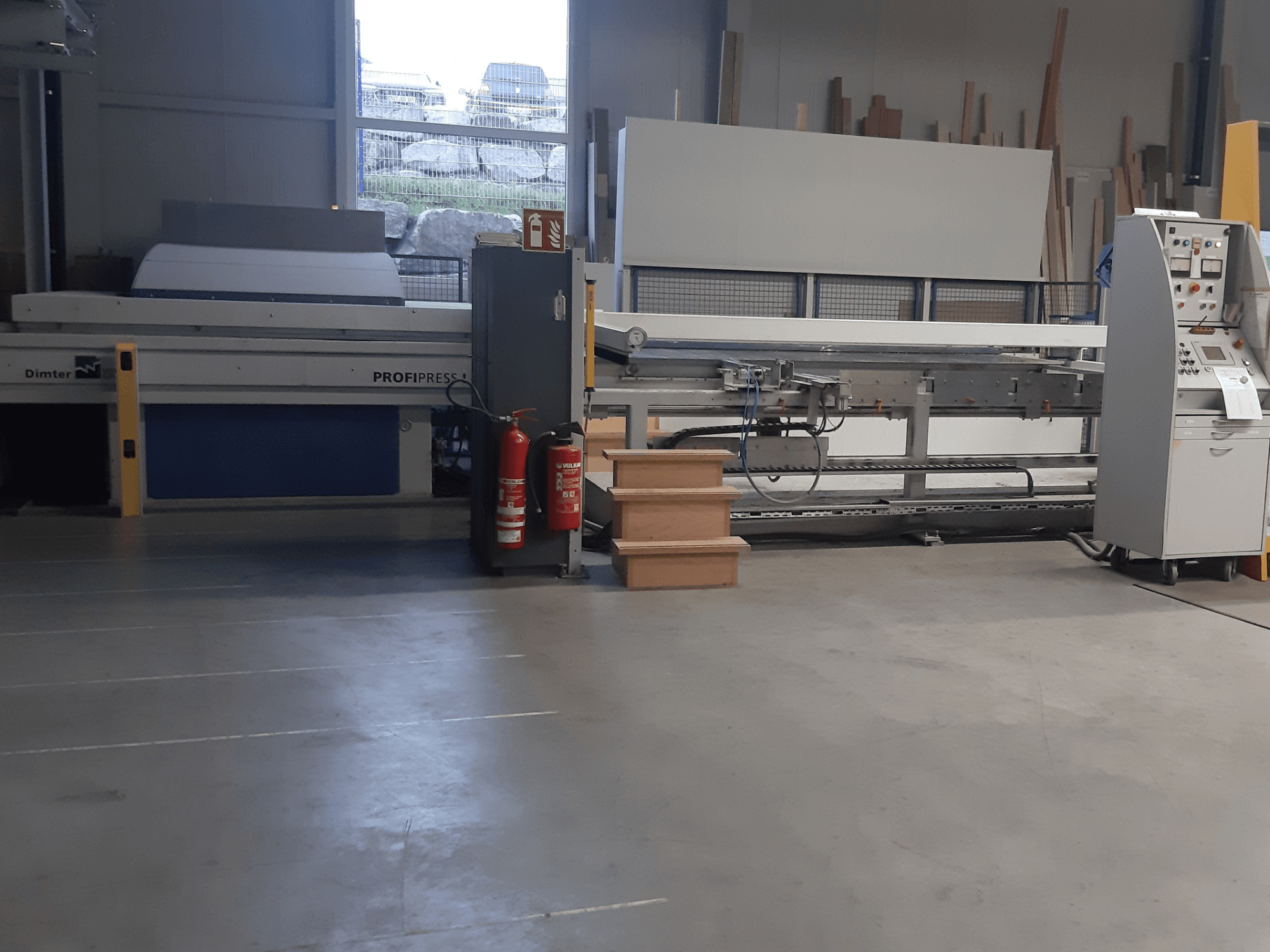 Машина Dimter ProfiPress у майстерні, вид спереду, з пультом керування та вогнегасниками поруч.