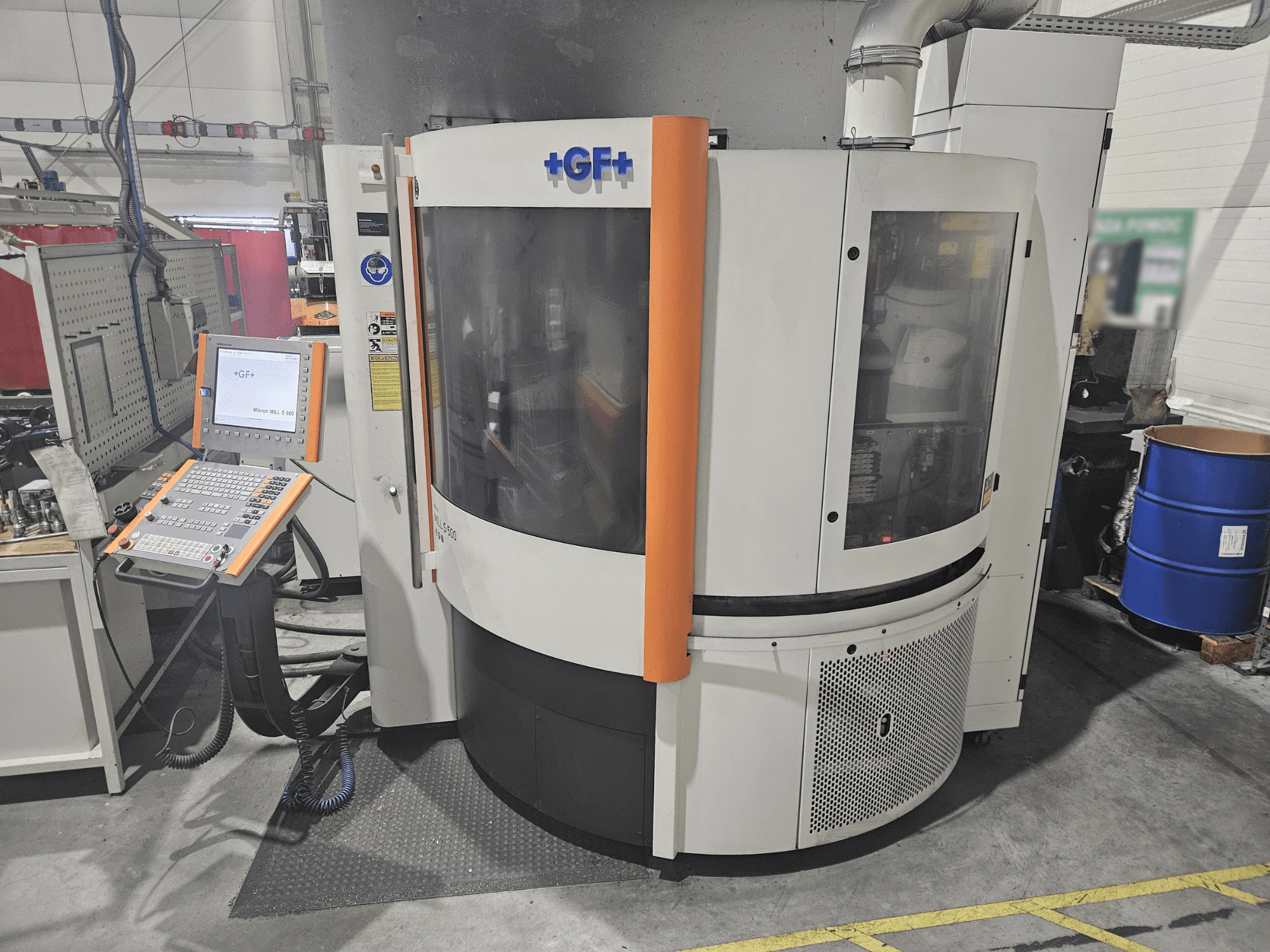 Верстат GF Machining Solutions з панеллю керування, вид спереду; має прозору панель, помаранчеві акценти та промислове налаштування.