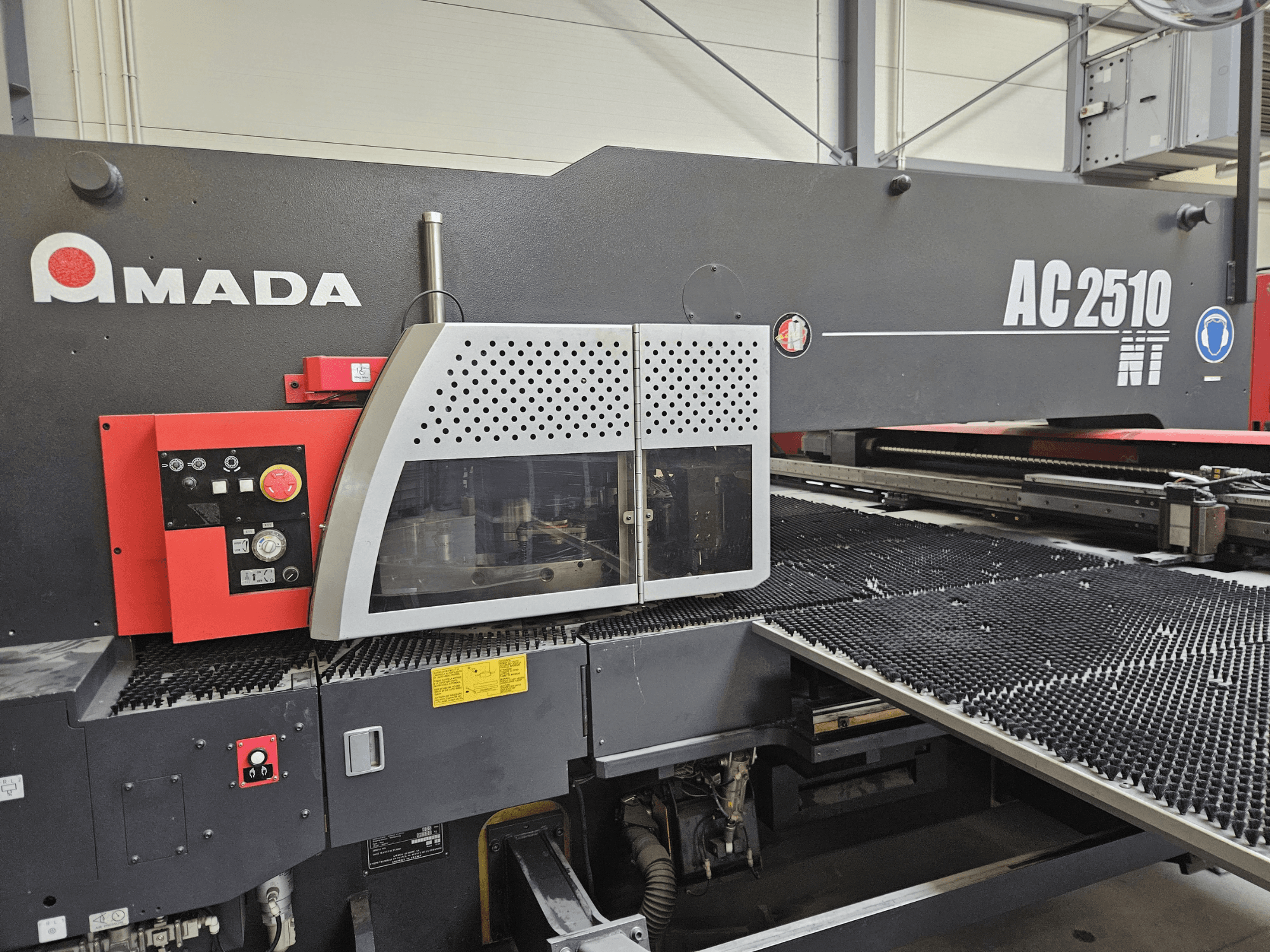 Лазерний розкрійний верстат Amada AC2510 NT, вигляд спереду, з панеллю керування з ручками, кнопками та захисною кришкою.