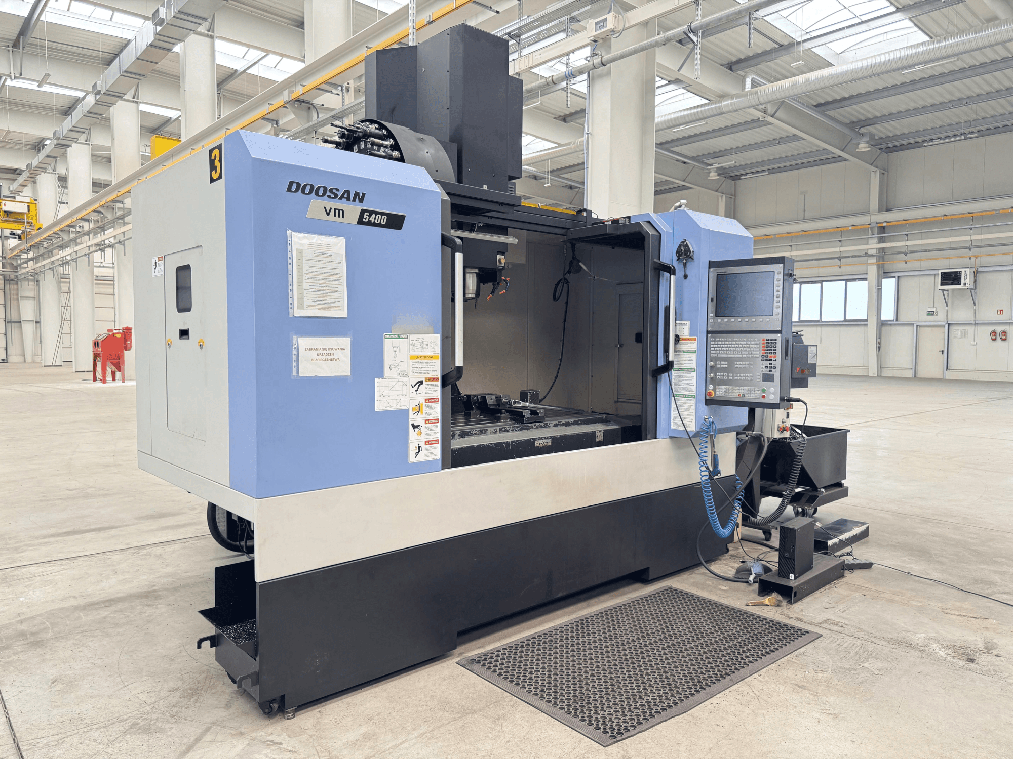 Вертикальний обробний центр DOOSAN VM 5400, вид спереду з панеллю керування та робочою зоною в просторому промисловому приміщенні.