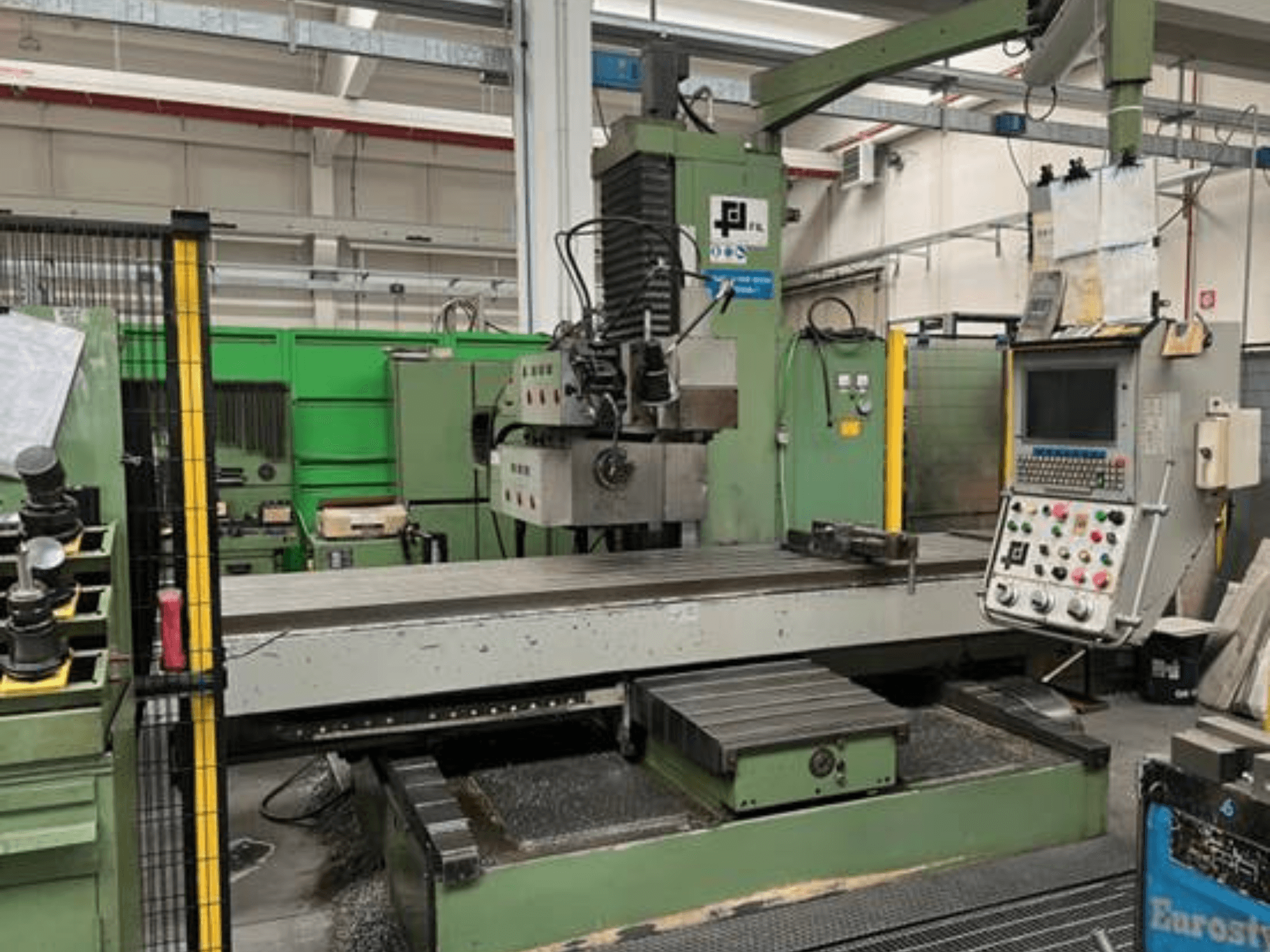 Промисловий фрезерний верстат від JFL, вид спереду з панеллю керування, великим плоским столом і металевою стружкою на підлозі.