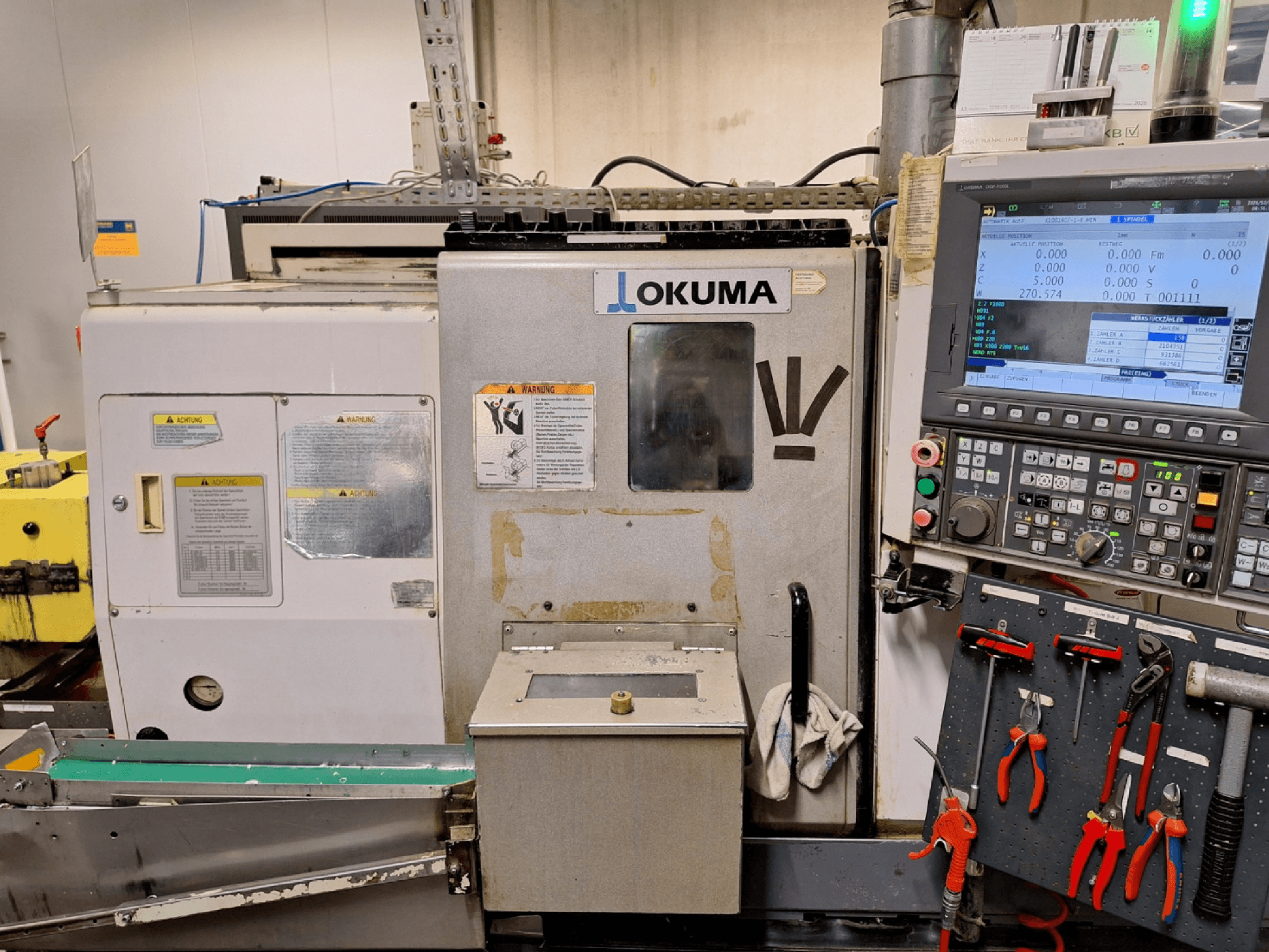 Горизонтальний токарний верстат Okuma LB200-MW, вид спереду, збоку видно панель управління та інструменти.