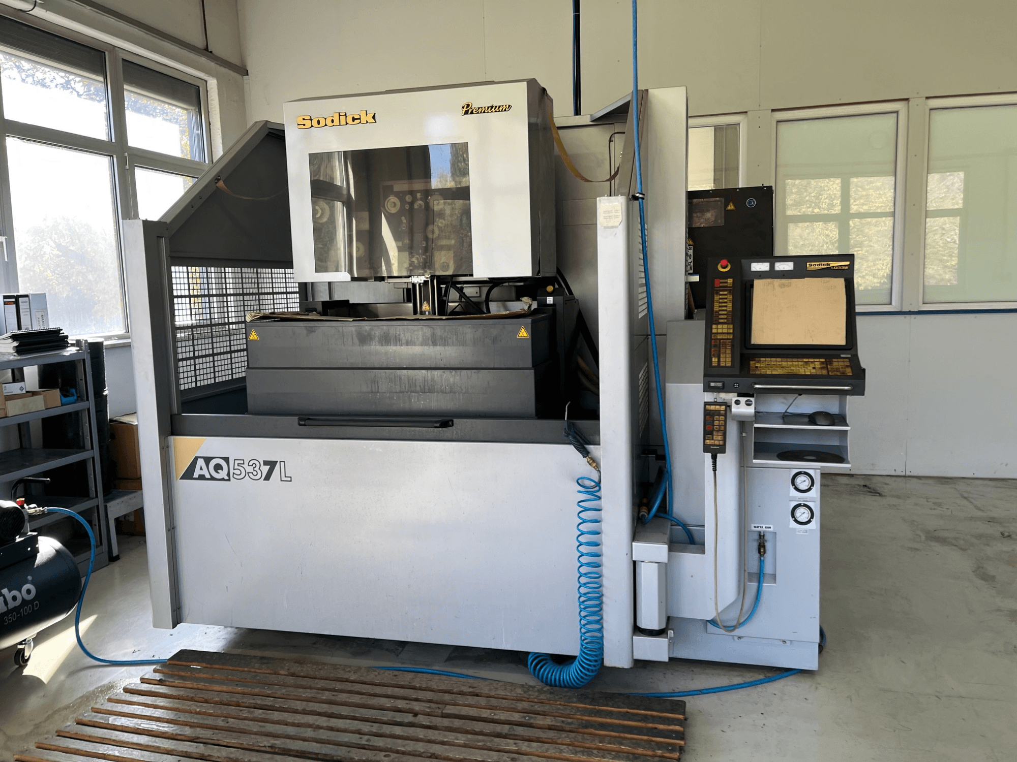 Електроерозійна машина (ЕЕМ) Sodick AQ537L спереду, з панеллю керування, лініями водяного охолодження та робочим простором.