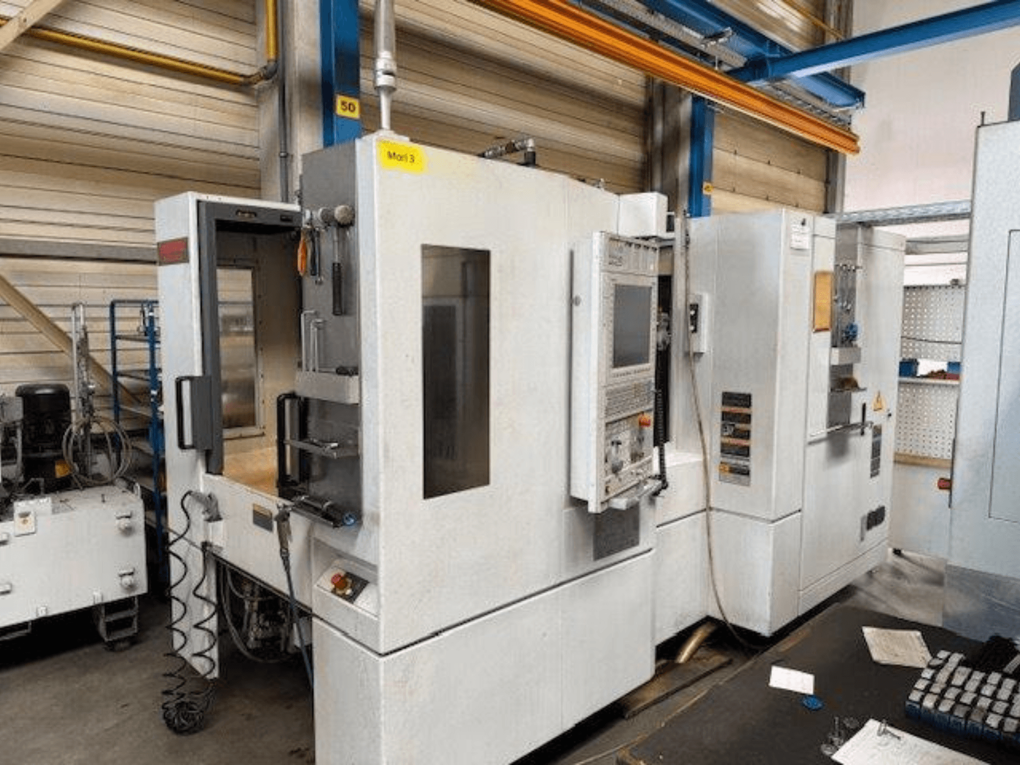 Вид спереду горизонтального обробного центру MORI SEIKI NH4000 DCG з відкритими дверцятами та панеллю керування, що демонструє робочий простір.