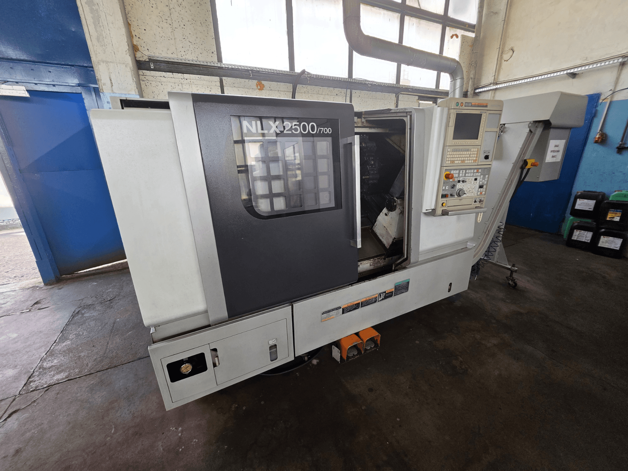 Горизонтальний токарний верстат DMG MORI NLX 2500/700 у боковому ракурсі, на якому видно панель управління та зону обробки.