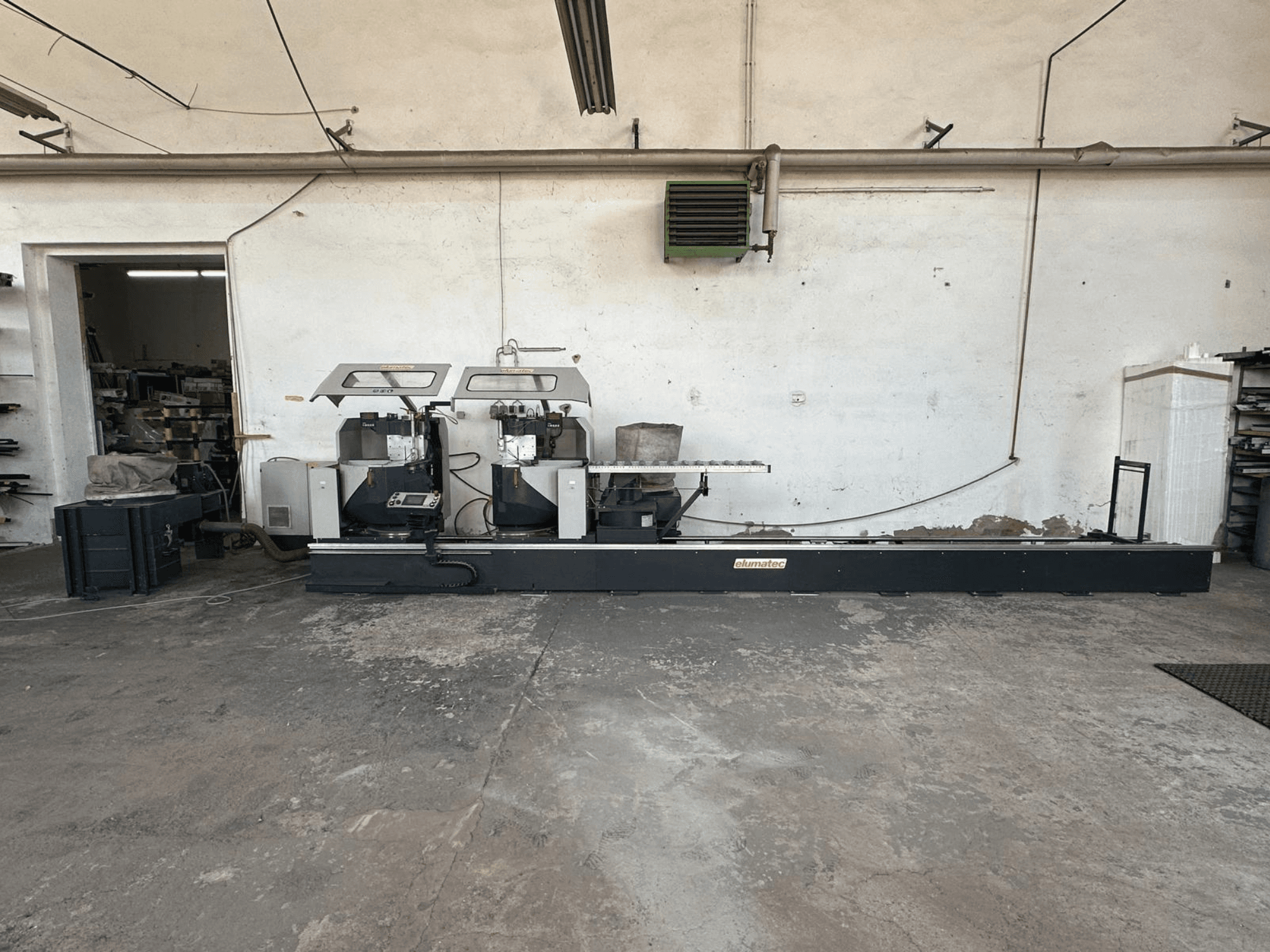 Циркулярна пила по металу Elumatec DG 244 в майстерні, вид збоку: дві пилки та елементи керування на міцній основі.