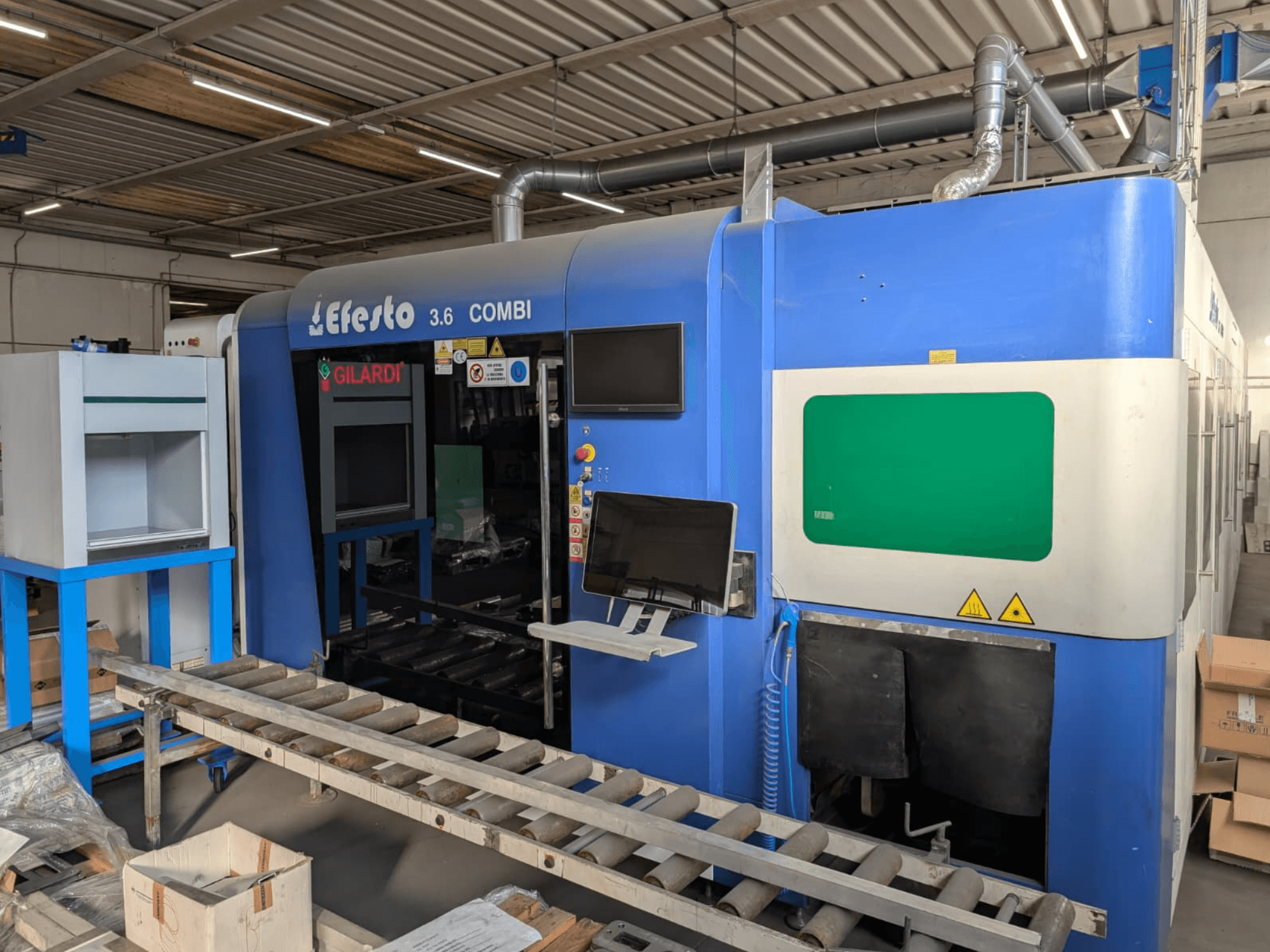 Машина для лазерного різання на волоконному лазері EFESTO 3.6 COMBI, вид збоку, з панеллю керування та індикаторами безпеки, у синьому кольорі.