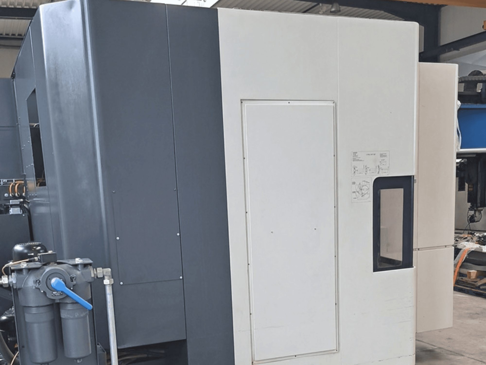 Горизонтальний обробний центр DMG MORI NHX5000, вид збоку, на якому видно панель керування та механічні елементи.