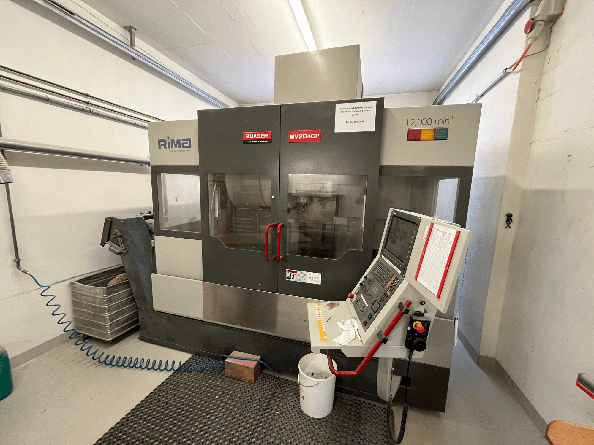 Вертикальний обробний центр Quaser MV-204 CP спереду, з панеллю керування та робочими деталями.