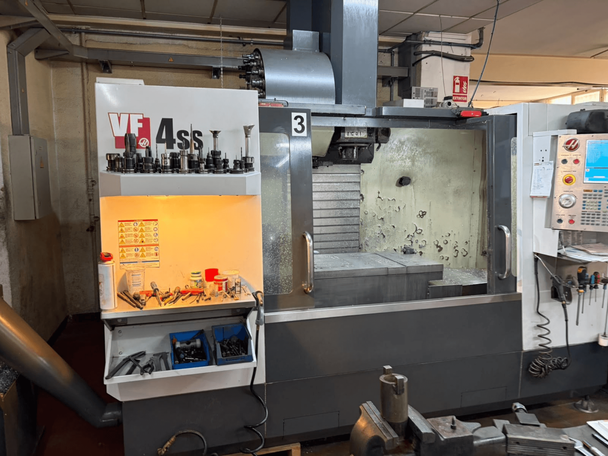 Вертикальний обробний центр HAAS VP 4SS, вид спереду, з відсіком для зберігання інструментів, панеллю керування та видимою робочою зоною з деталями обробки.