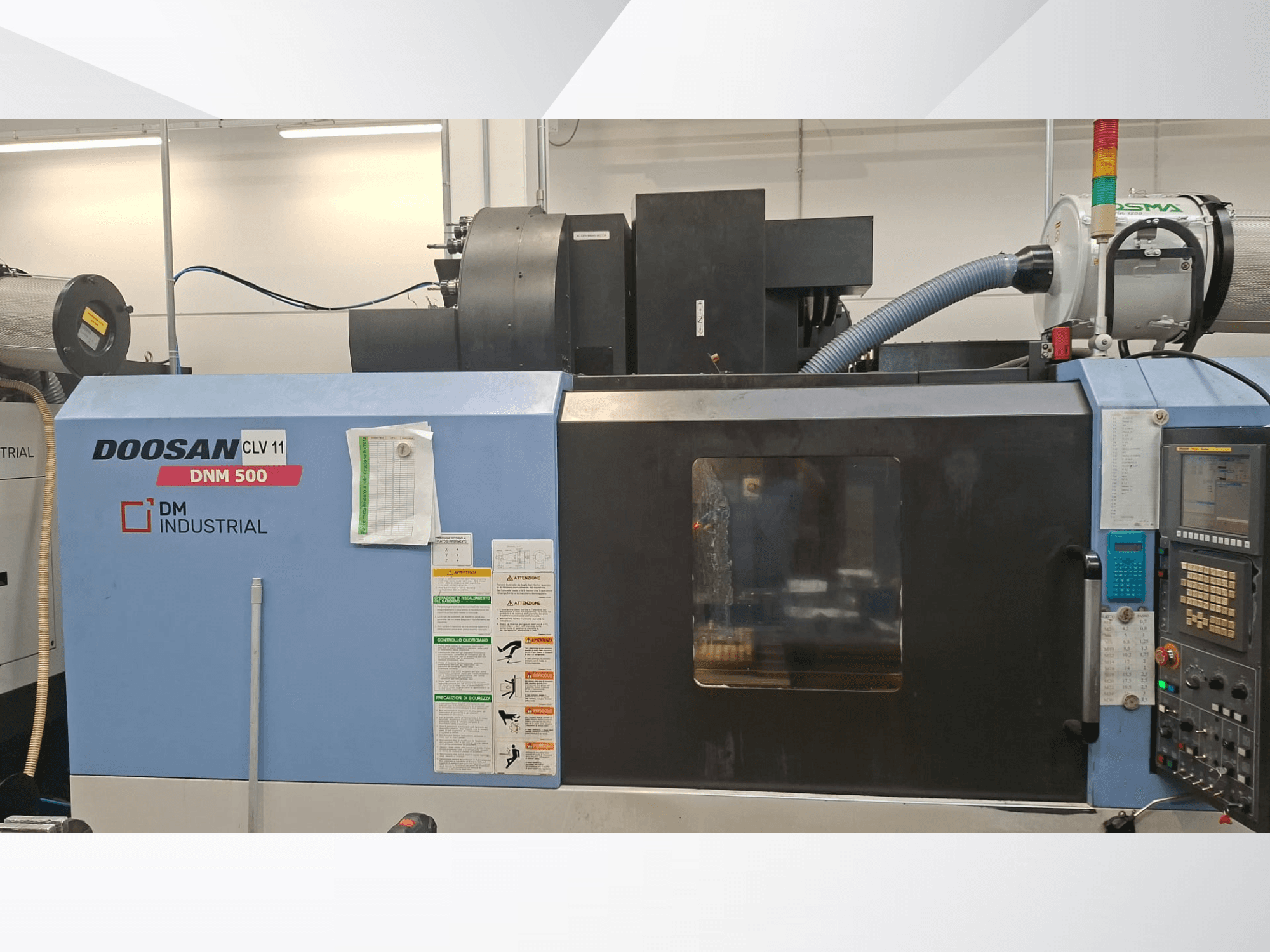 Вертикальний обробний центр DOOSAN DNM 500 у боковому ракурсі, на якому видно панель управління та робочі елементи.