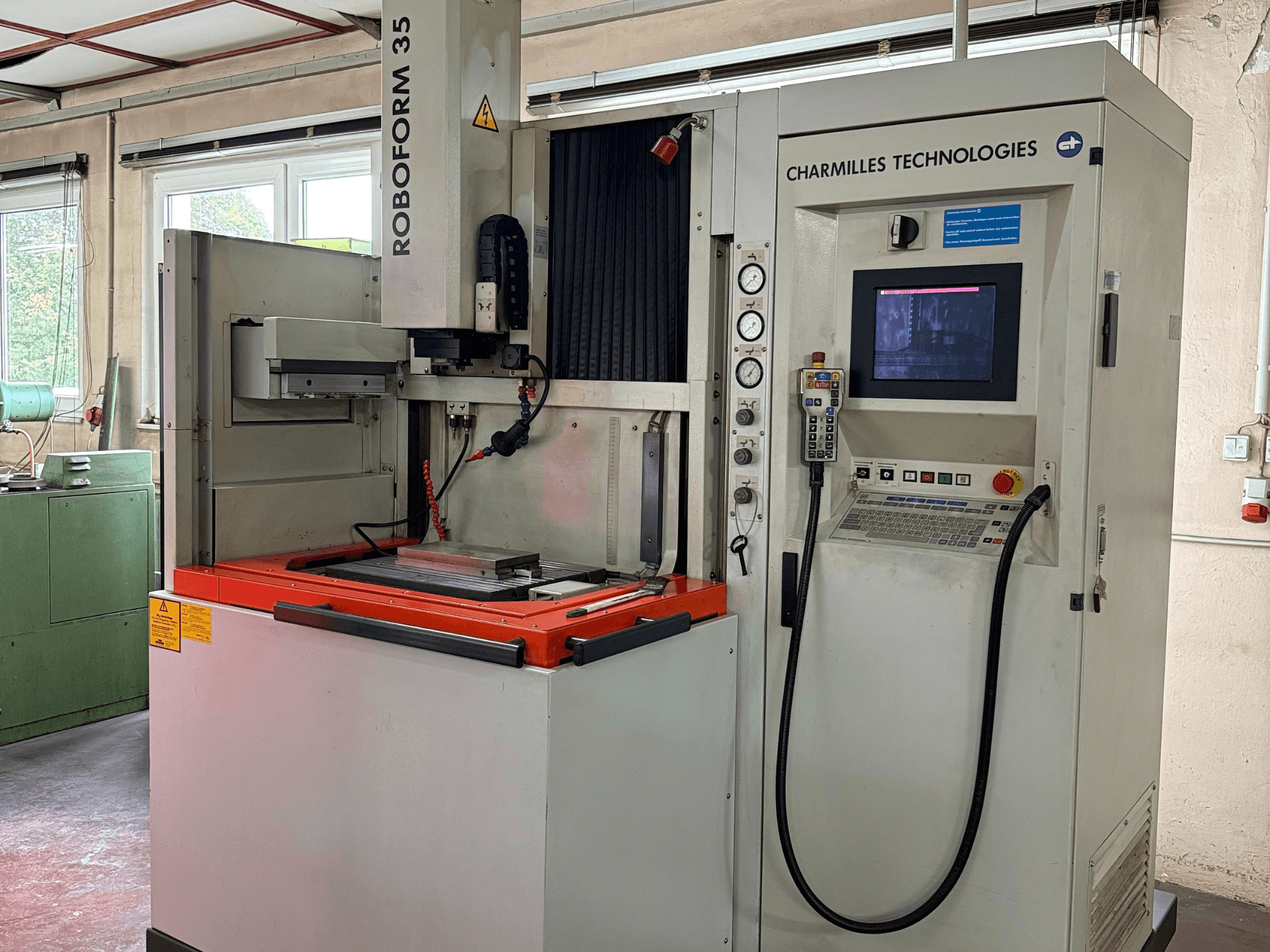 Верстат Charmilles Technologies Roboforn 35, вид спереду, з панеллю керування, встановленими інструментами та етикетками безпеки.