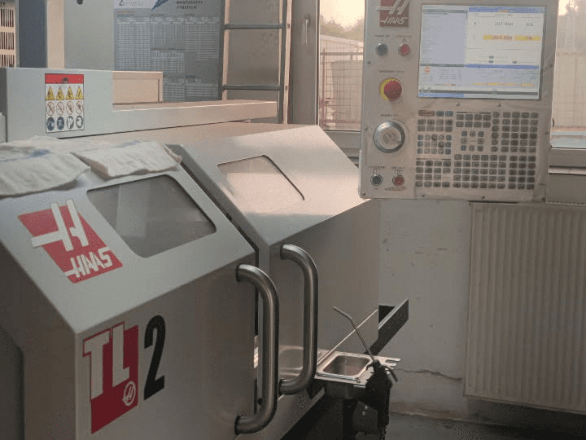 Горизонтальний токарний верстат Haas TL-2, вид спереду, з панеллю керування, металевим корпусом і знаками безпеки.