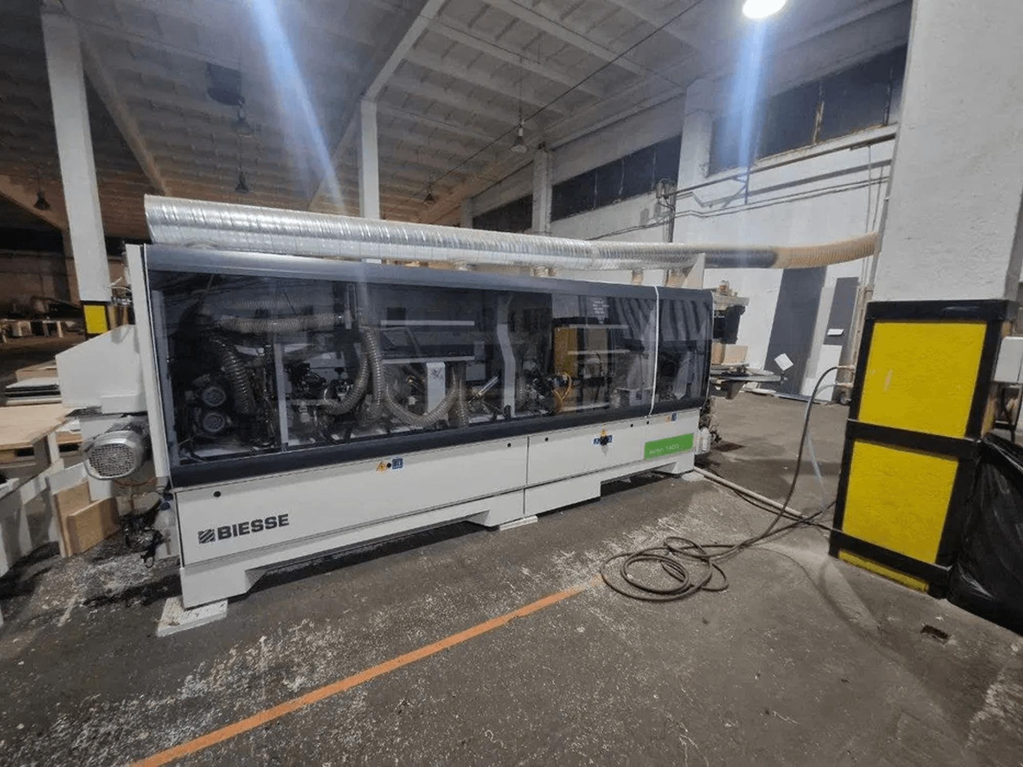 Кромкооблицювальна машина BIESSE Akron 1440 A у цеху, з прозорою кришкою та відкритими механічними вузлами.