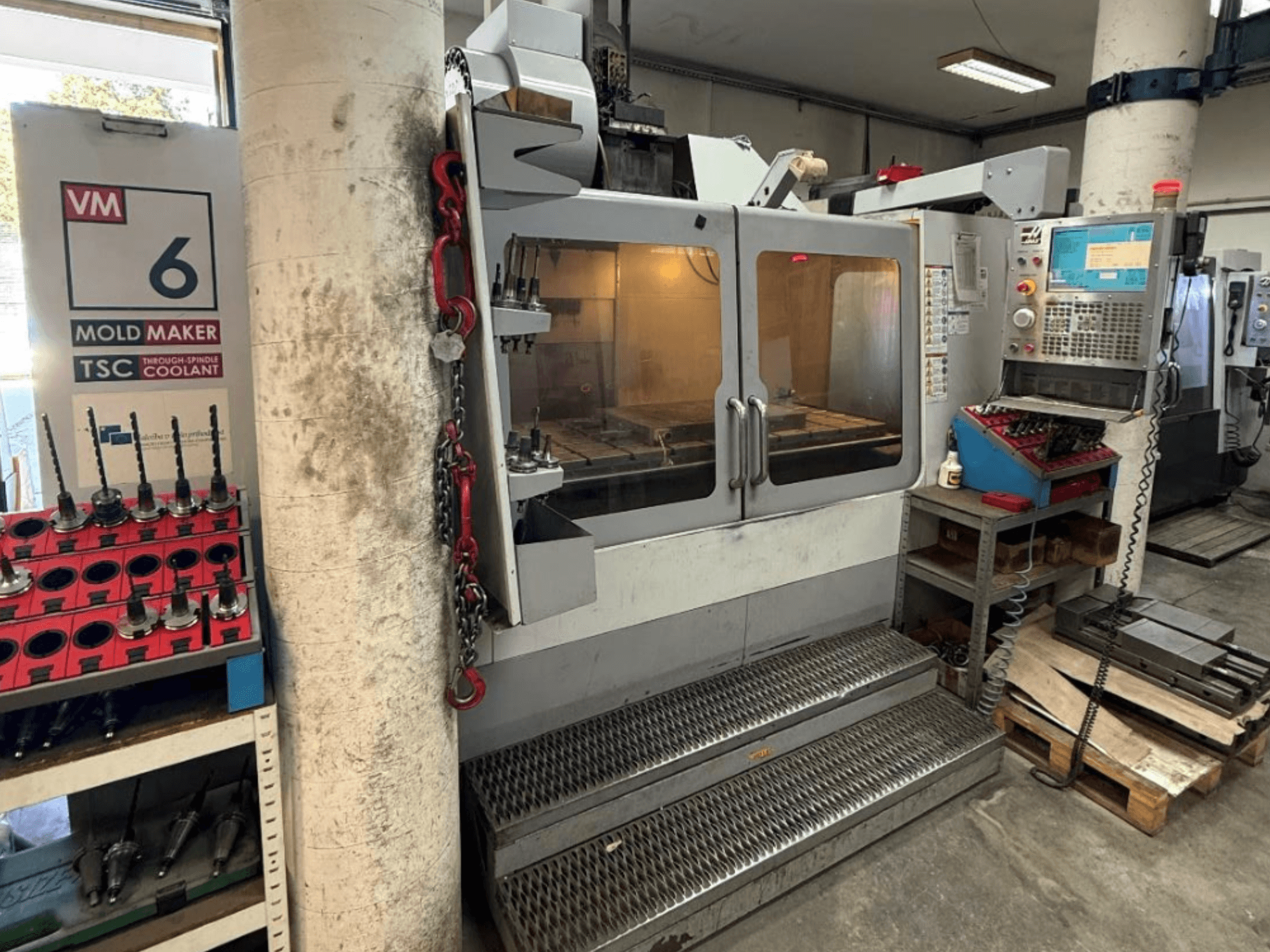 Вертикальний обробний центр HAAS VM-6 HE у фронтальному ракурсі: видно панелі управління, систему охолодження та сховище інструментів.