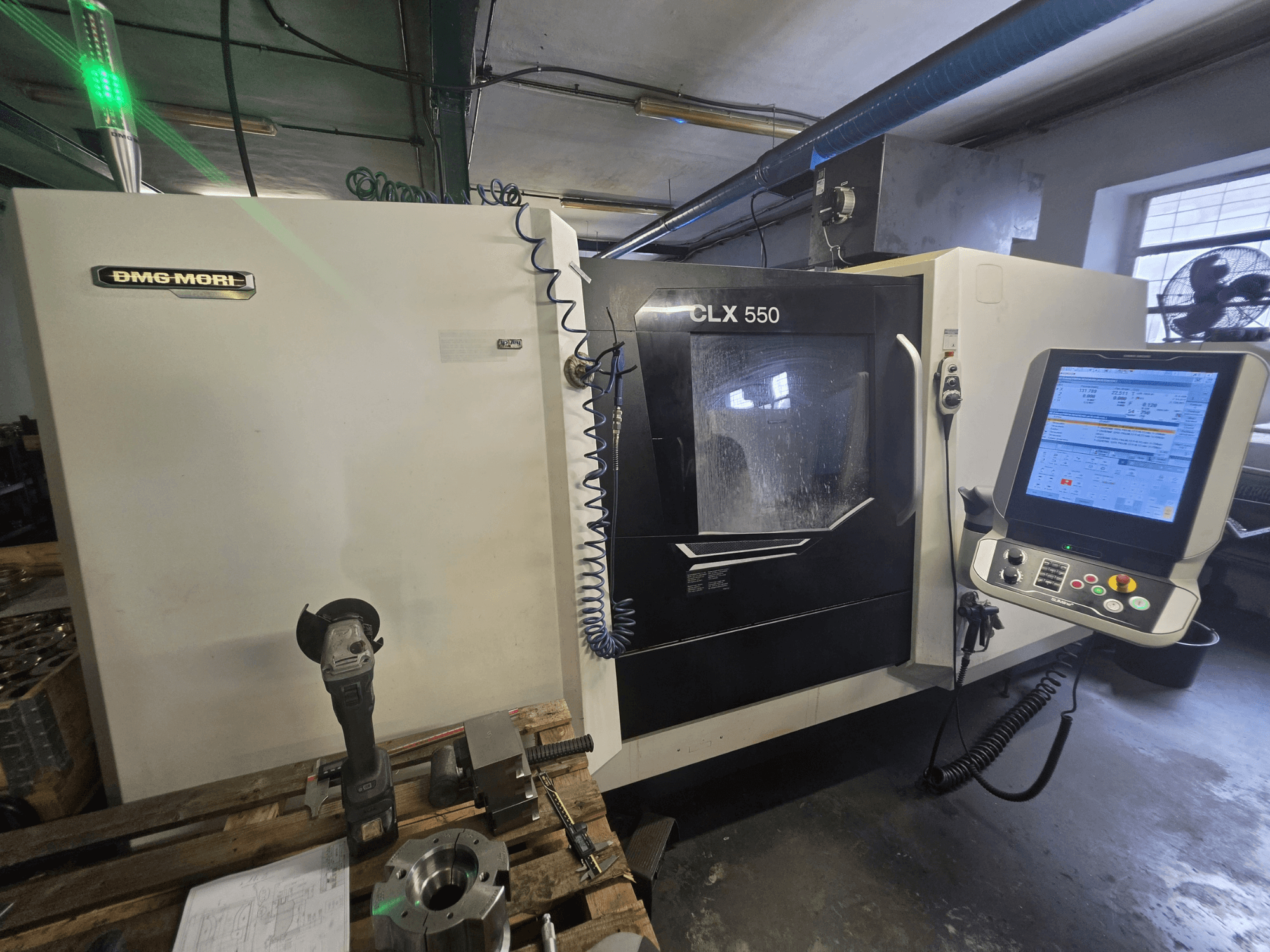 Горизонтальний токарний верстат DMG MORI CLX 550 V3, вид спереду, на якому видно панель керування, ріжучі інструменти та корпус верстата.