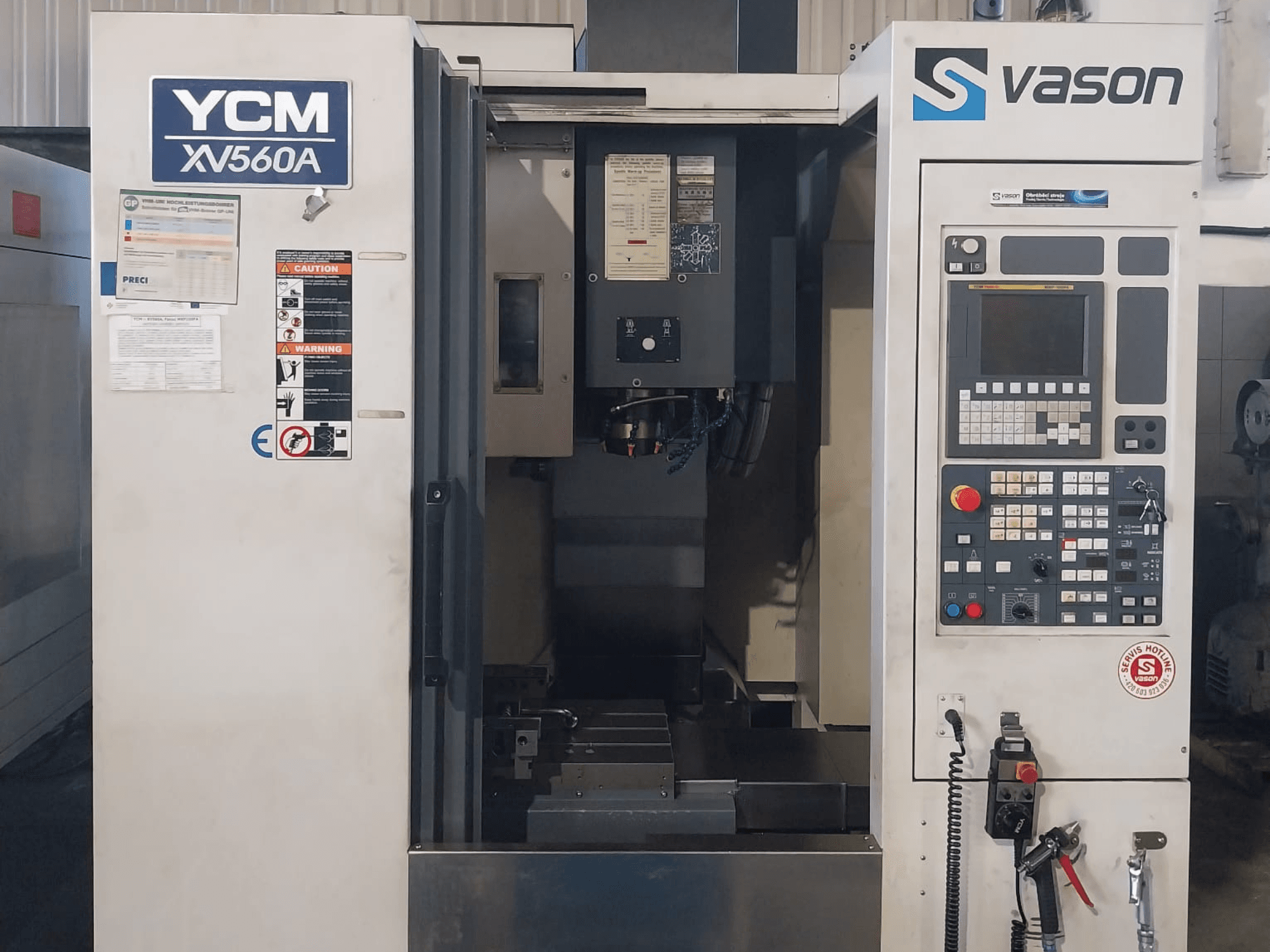 Вертикальний обробний центр YCM XV 560A спереду, з панеллю керування та робочим столом, на якому видно компоненти обробки.