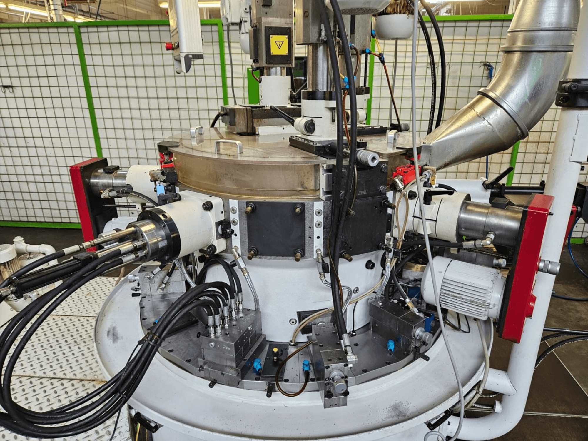 Крупним планом промислова машина з гідравлічними шлангами, металевими компонентами та основою, що обертається. Торгову марку не видно.