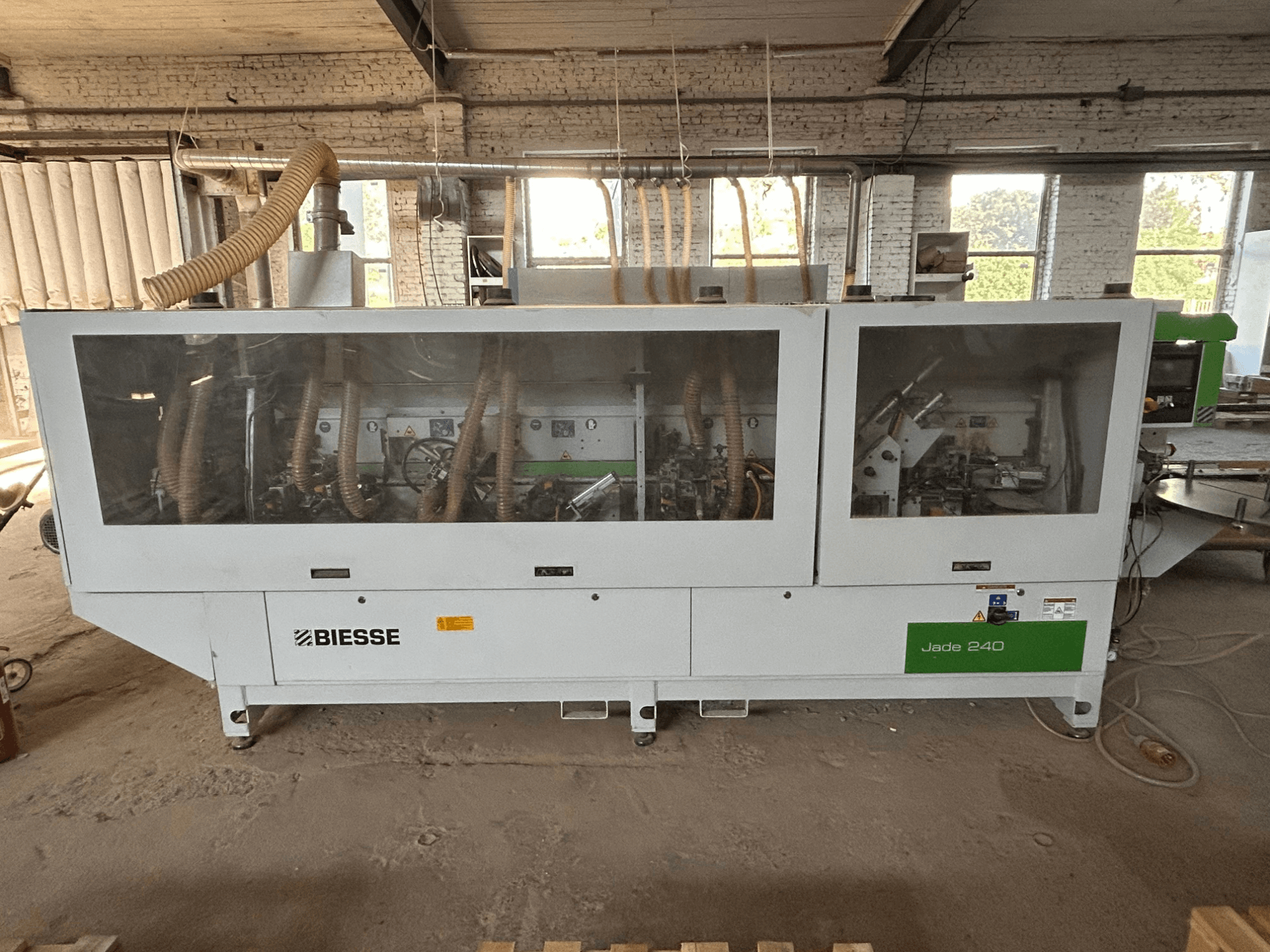 Обклеювальна машина BIESSE Jade 240 у біло-зеленому кольорі, вид спереду з панеллю управління та детальною конструкцією механізму всередині.