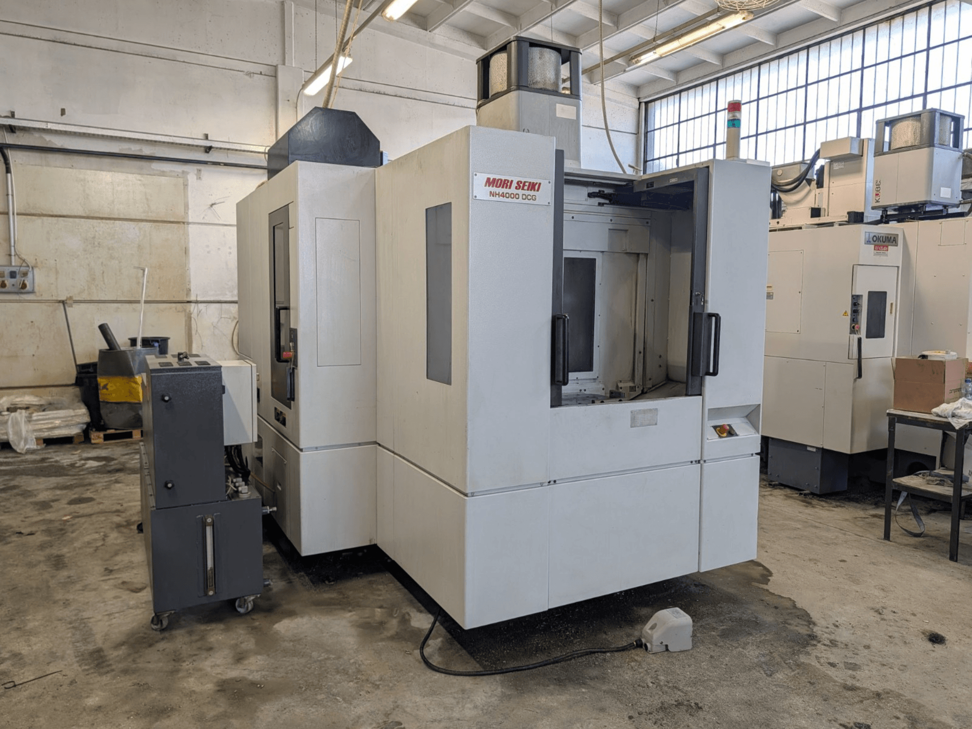 Горизонтальний обробний центр MORI SEIKI NH 4000 DCG, вид спереду, демонструє панель керування та робочу зону, сіро-біле покриття.