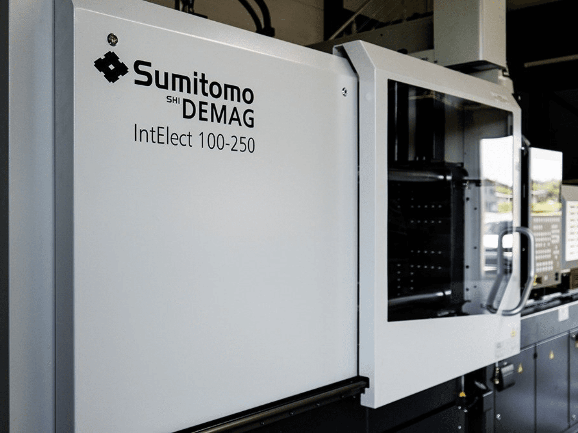 Вигляд спереду електричної термопластавтомата SUMITOMO SHI DEMAG IntElect 100/250 з панеллю керування та засобами безпеки.