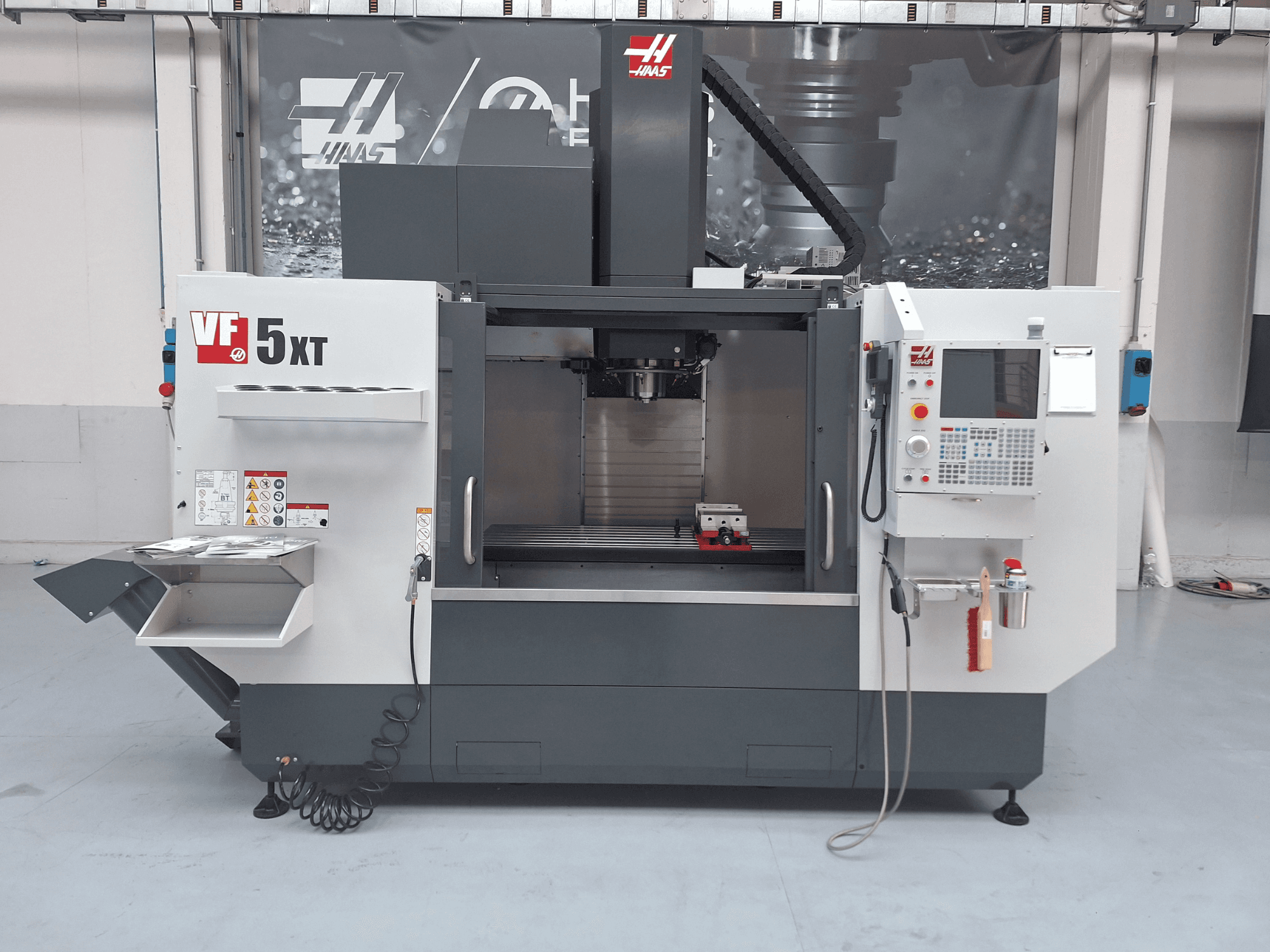 Вертикальний обробний центр HAAS VF-5/50XT, вид спереду, на якому видно панель управління, зону шпинделя та відсік для зберігання інструментів.