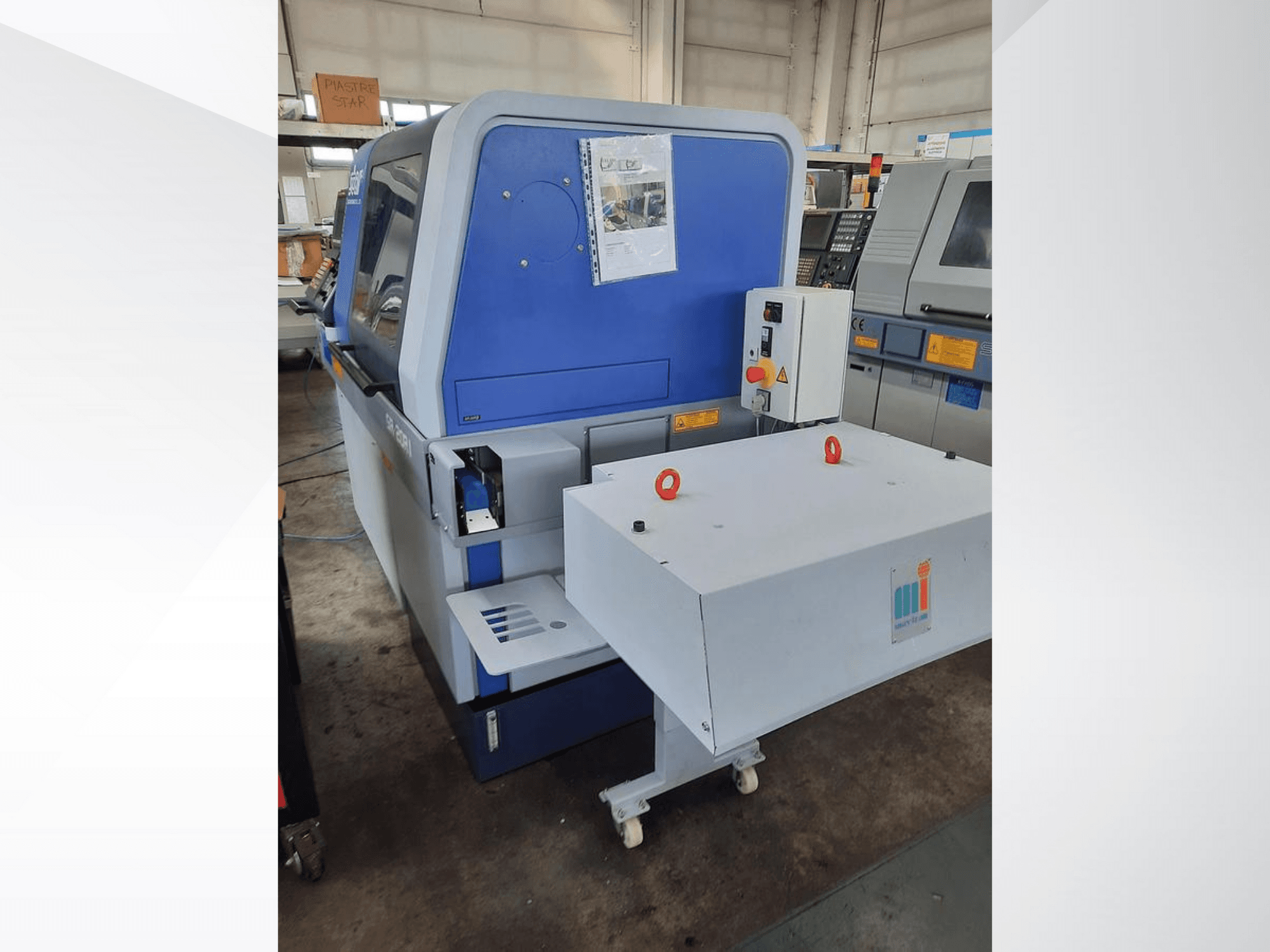 Синя промислова машина з білим конвеєром, на якій показано панель управління та прикріплені засоби безпеки, вид збоку.