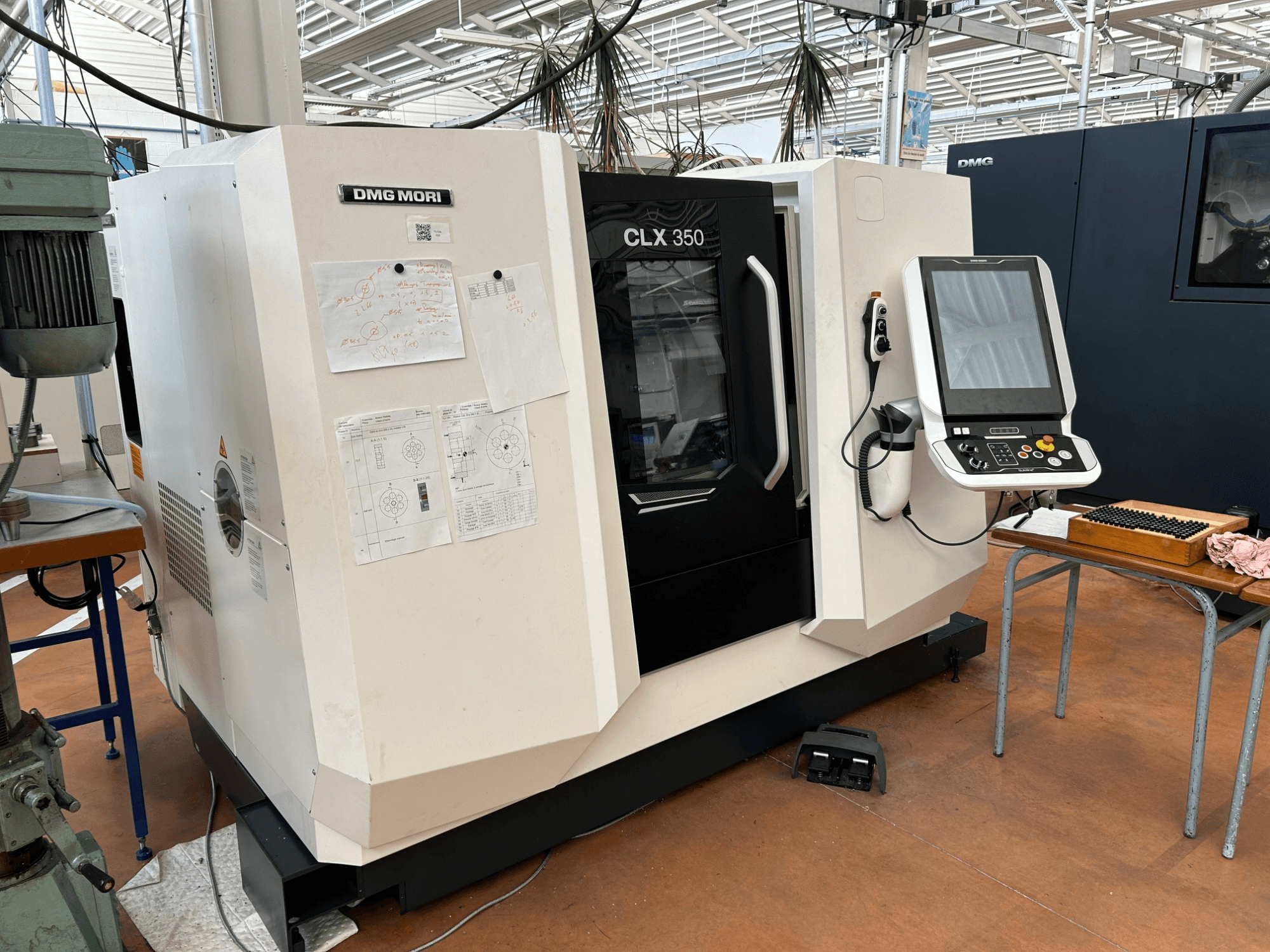 Горизонтальний токарний верстат DMG MORI CLX 350 V4, вид спереду з панеллю керування та доданою технічною документацією.