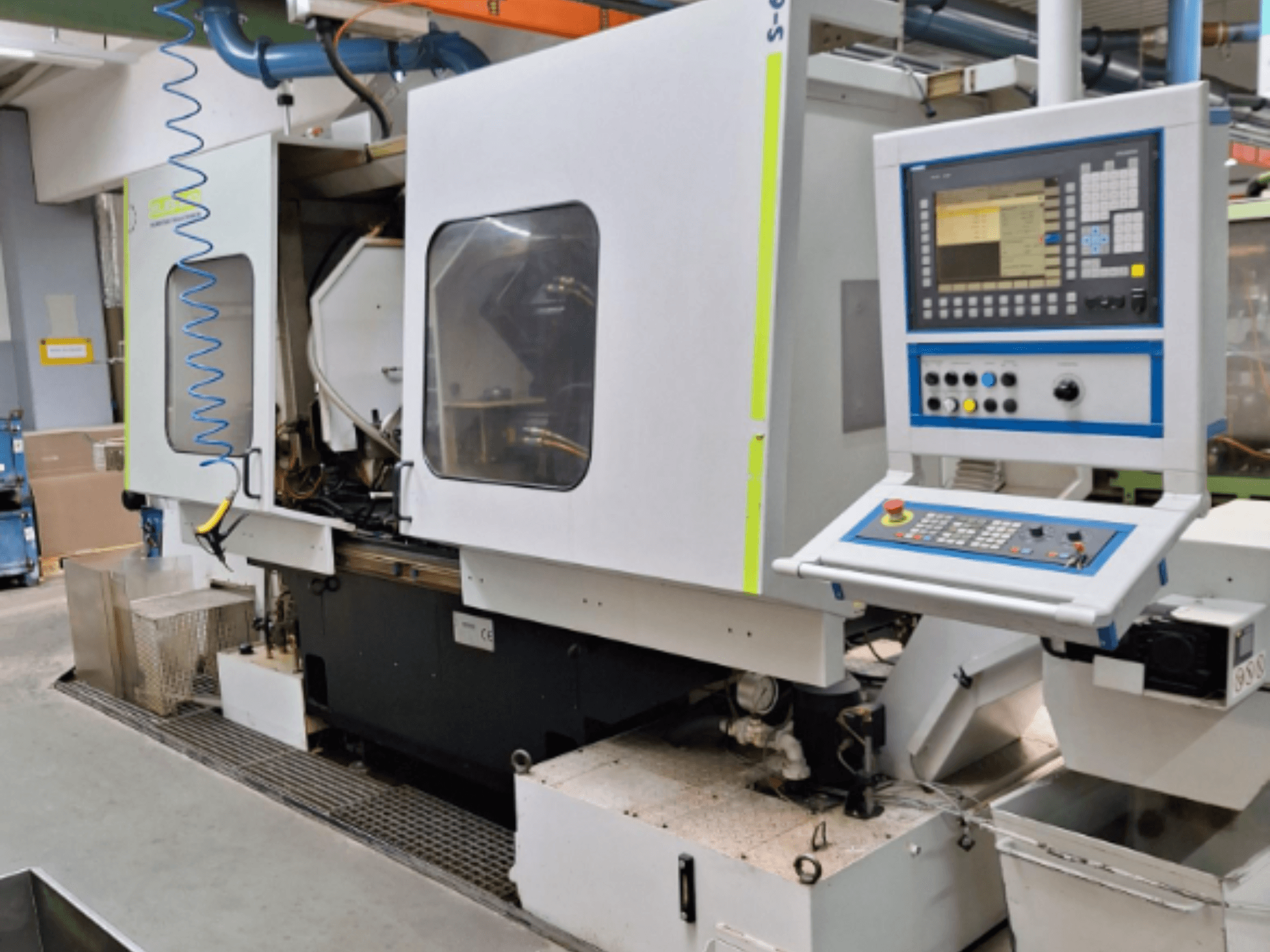 Промисловий фрезерний верстат з панеллю керування, вид збоку, з двома камерами і видимими з'єднаннями трубопроводів.