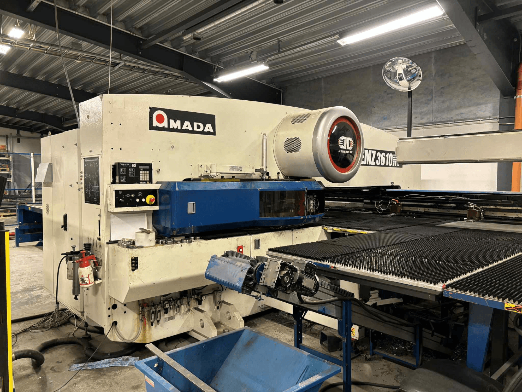 Вирубний прес Amada EMZ3610H, вид спереду; оснащений органами керування, синьою станиною та засобами безпеки.