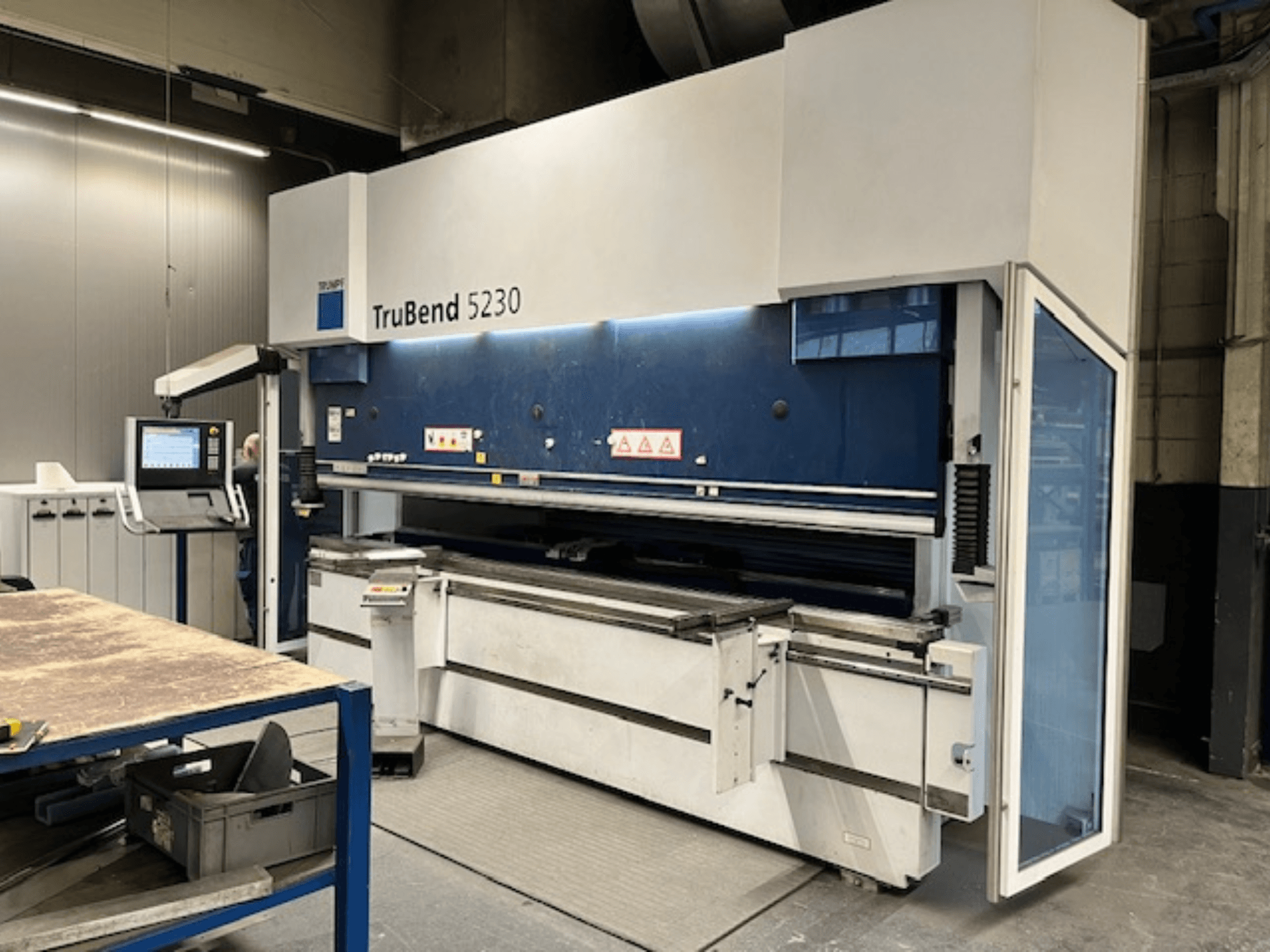 Згинальний верстат TruBend 5230 в промислових умовах; вид спереду з панеллю керування, елементами безпеки та робочим столом.