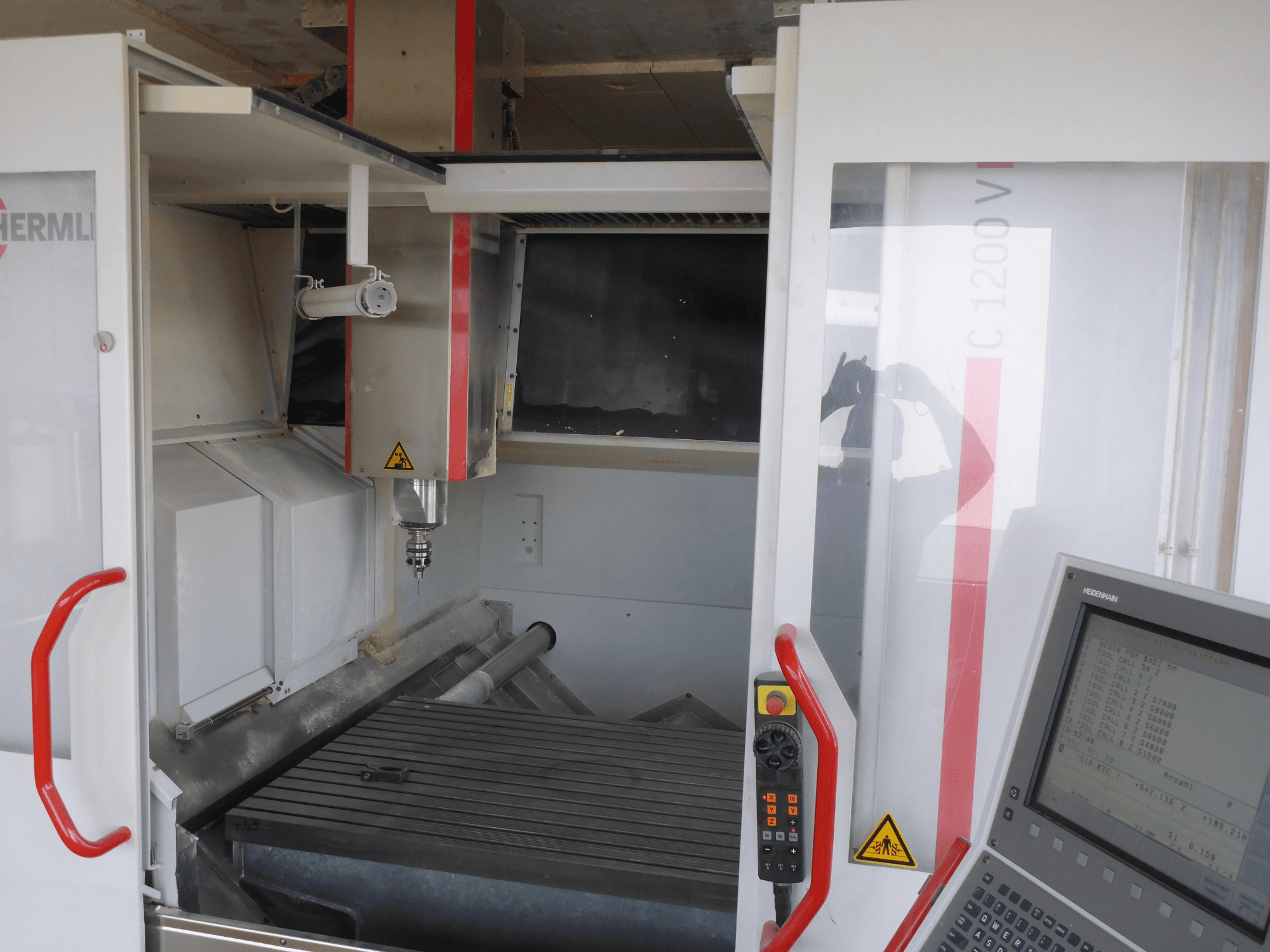 Інтер'єр вертикального обробного центру HERMLE C 1200: тримач інструменту, панель керування та робочий стіл спереду.