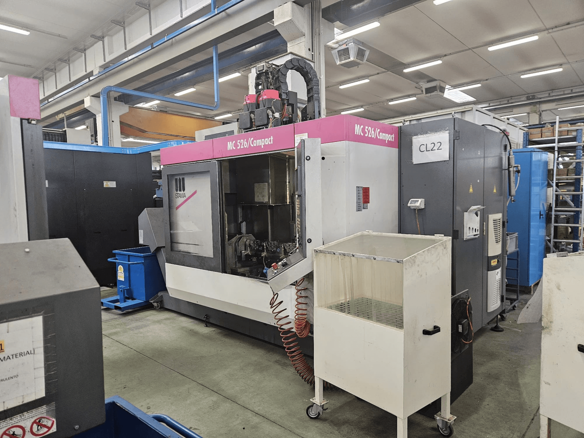 Компактний верстат з ЧПК MC 526 від Stama, вид збоку, з панеллю керування, баком для охолоджувальної рідини та суміжними механізмами.