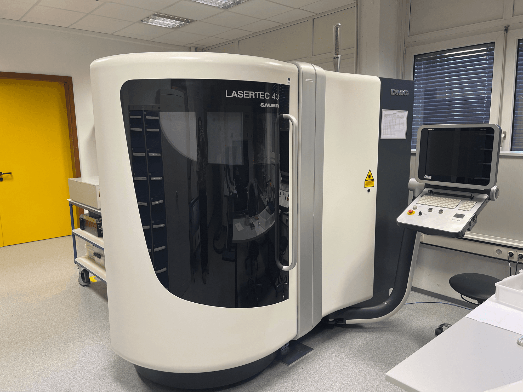 Білий фрезерний верстат LASERTEC 40 від DMG MORI, вид спереду, з панеллю керування та ергономічним дизайном для роботи в добре освітленому приміщенні.