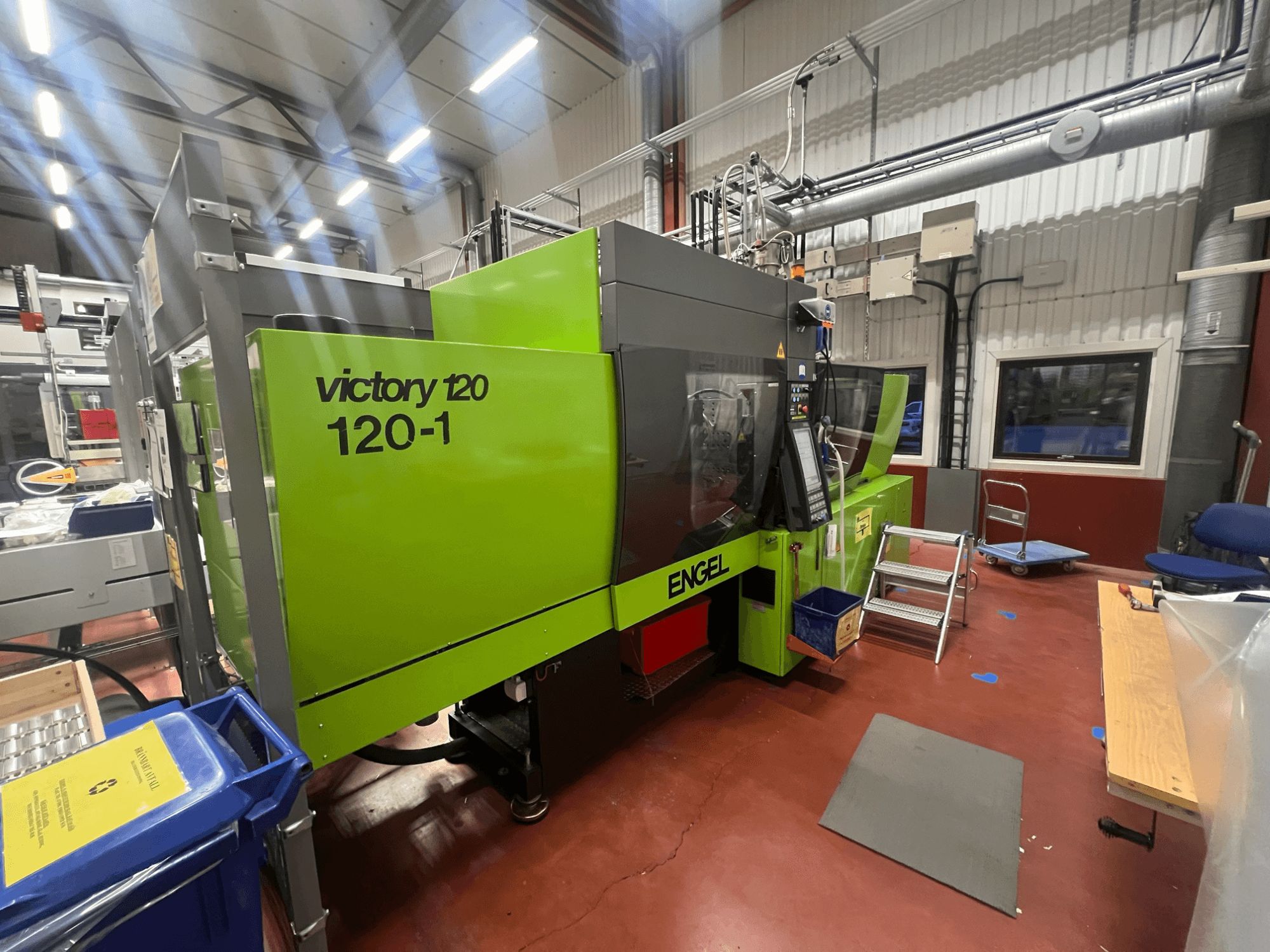 Зелена термопластавтомат ENGEL Victory 120-1, вид спереду, з панеллю керування та сходинками, в промислових умовах.