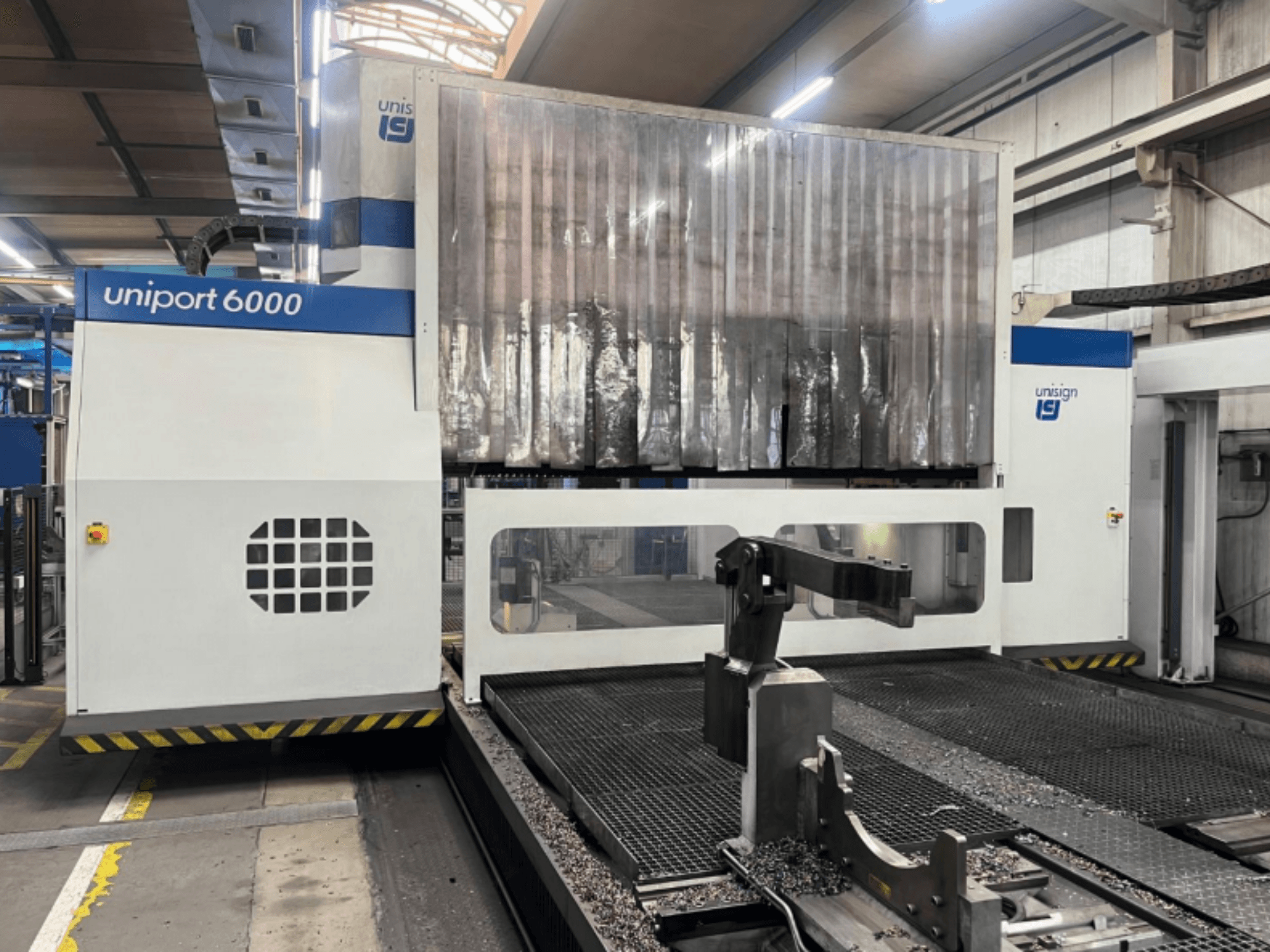 Портальний фрезерний верстат Unisign uniport 6000, вид спереду, демонструє структуру верстата і зону різання металевою стружкою.