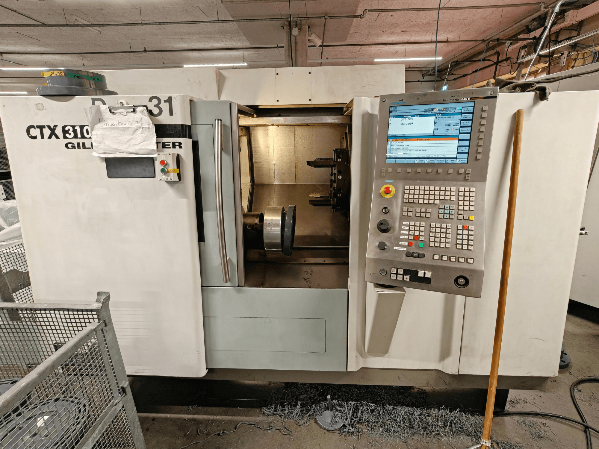 Горизонтальний токарний верстат Gildemeister CTX 310, вид спереду з панеллю керування, що показує інструменти та робочий простір всередині.