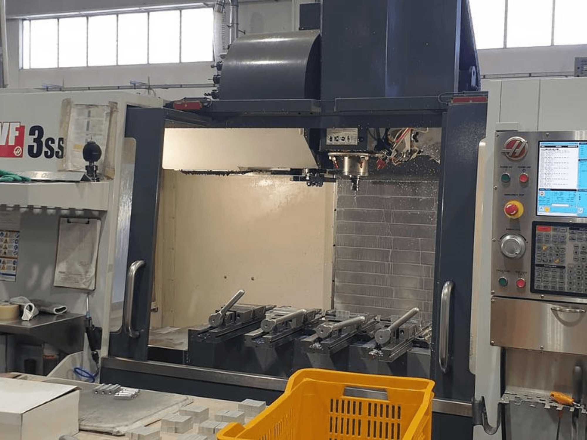 Вертикальний обробний центр HAAS VF-3SS, вид спереду з панеллю керування ЧПУ, інструментами та помаранчевим кошиком.