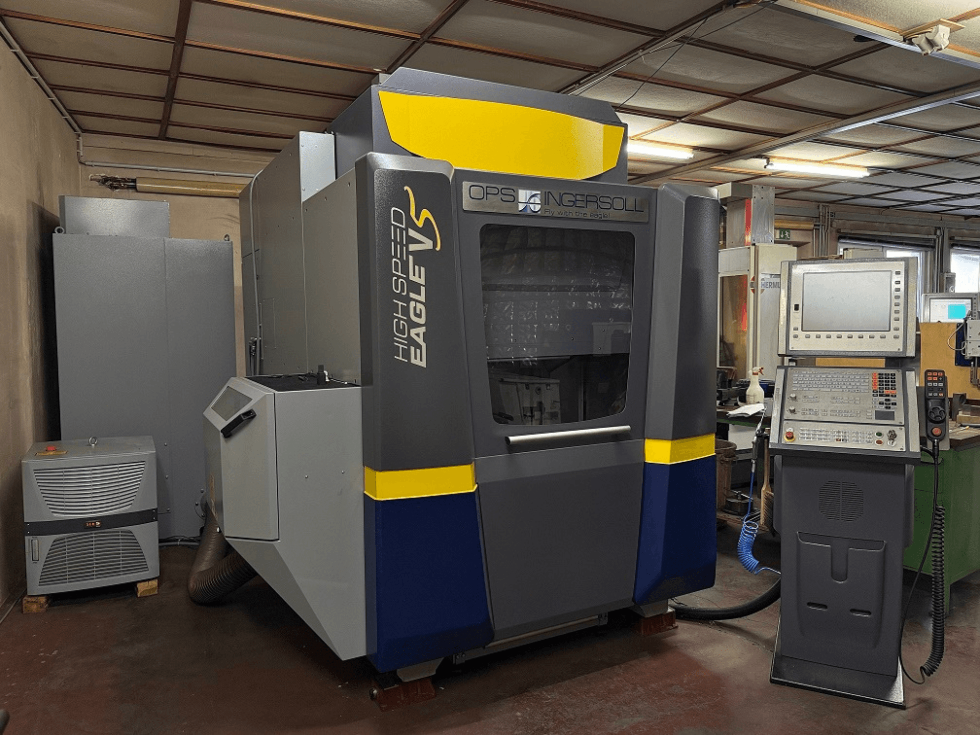 Високошвидкісний верстат Eagle V від OPS Ingersoll, вид збоку, з панеллю керування та суміжним обладнанням у промислових умовах.